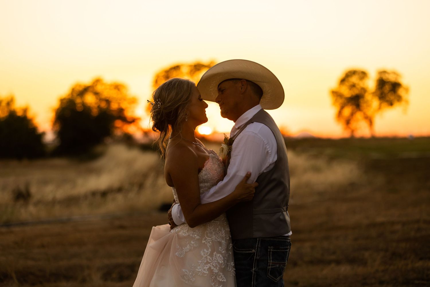 Romantic silhouette of a couple embracing during sunset in a country field.