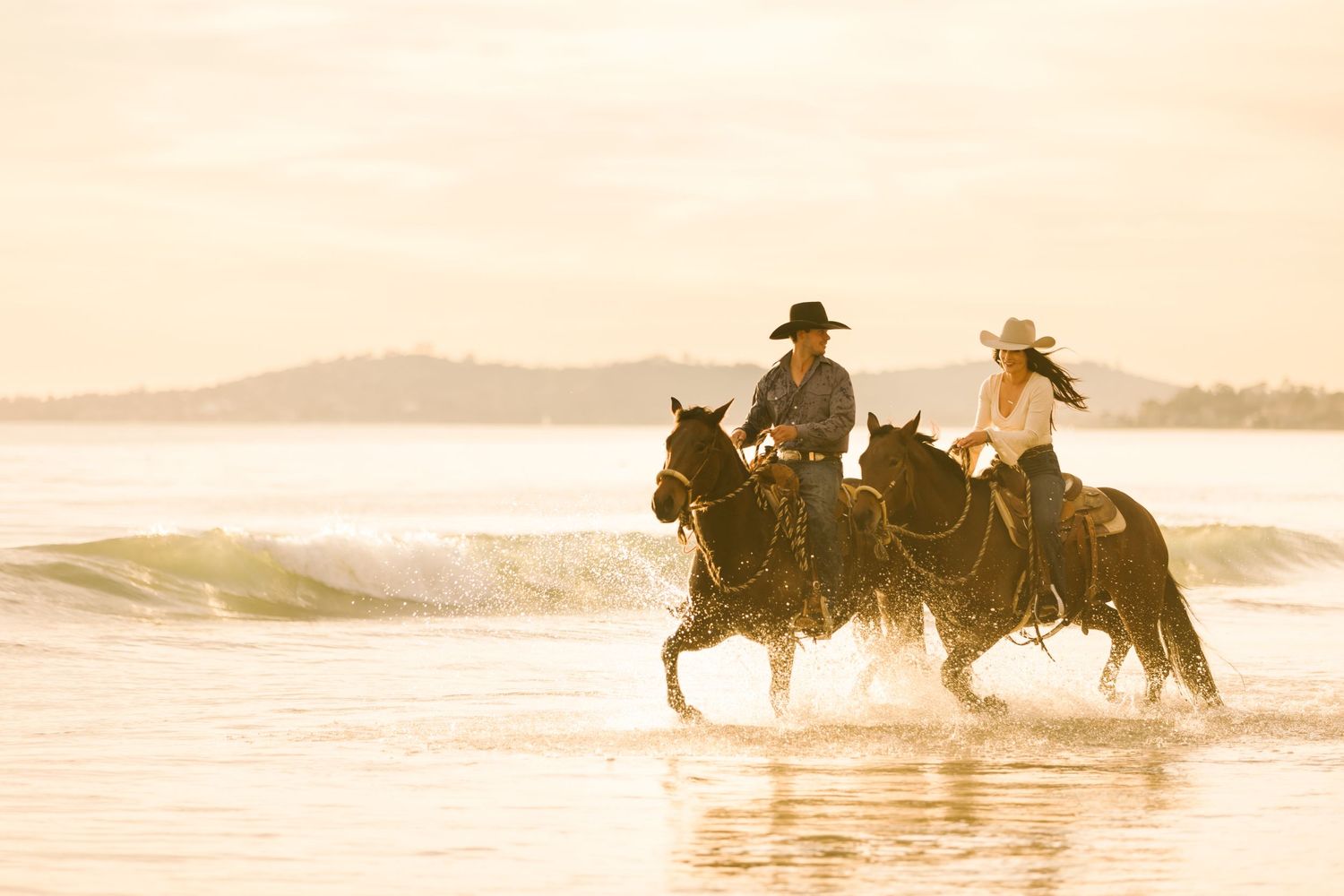 Cowboy and cowgirl riding their horses through the water being photographed by California Horse Photographer Lauren Wagner