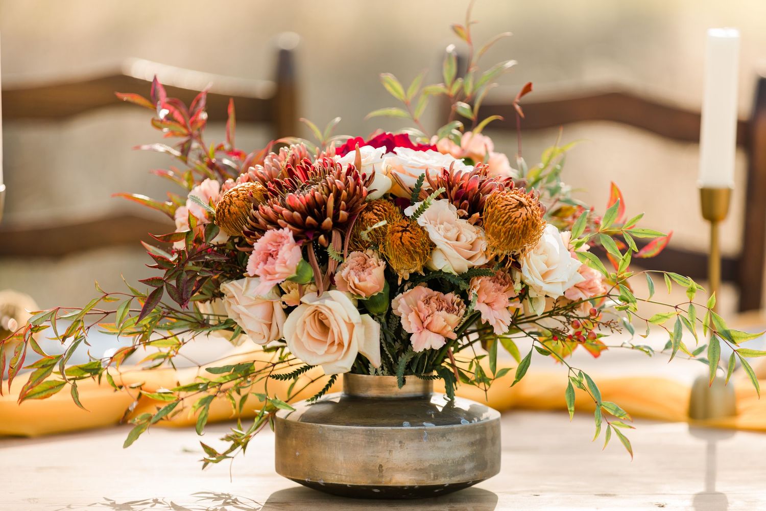 Low floral wedding centerpiece arrangement with pink and white flowers in a metallic vessel on wooden table.