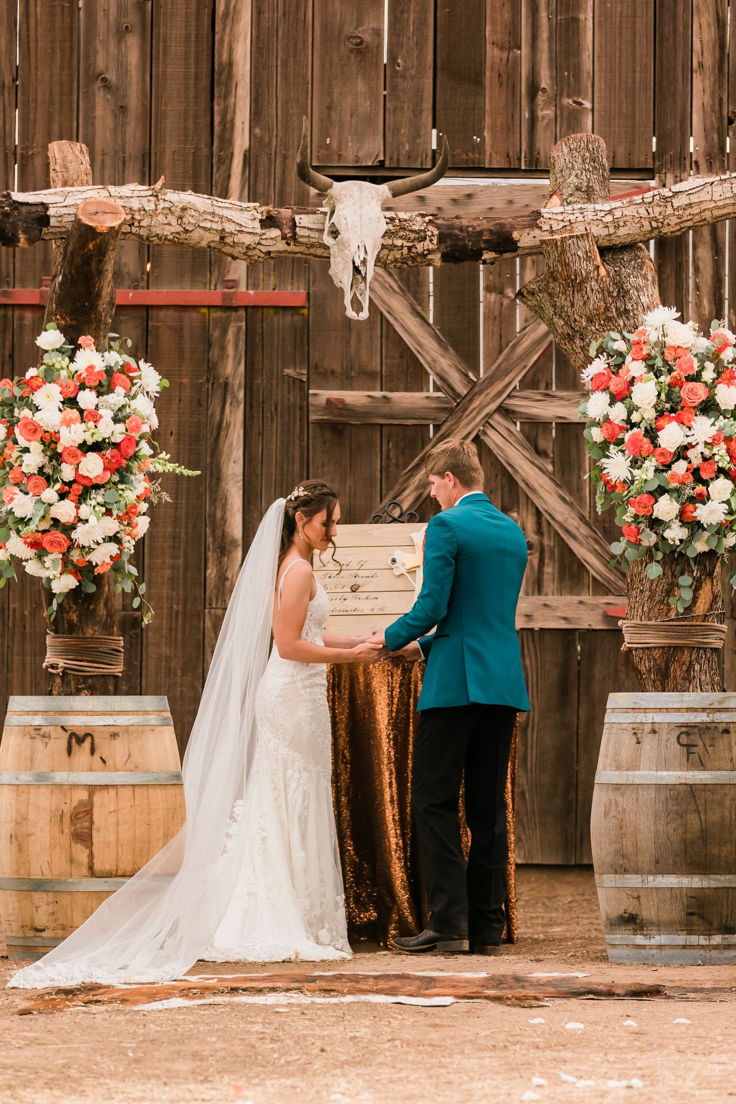 Wedding ceremony inside a rustic wooden barn decorated with pink and cream floral arrangements.