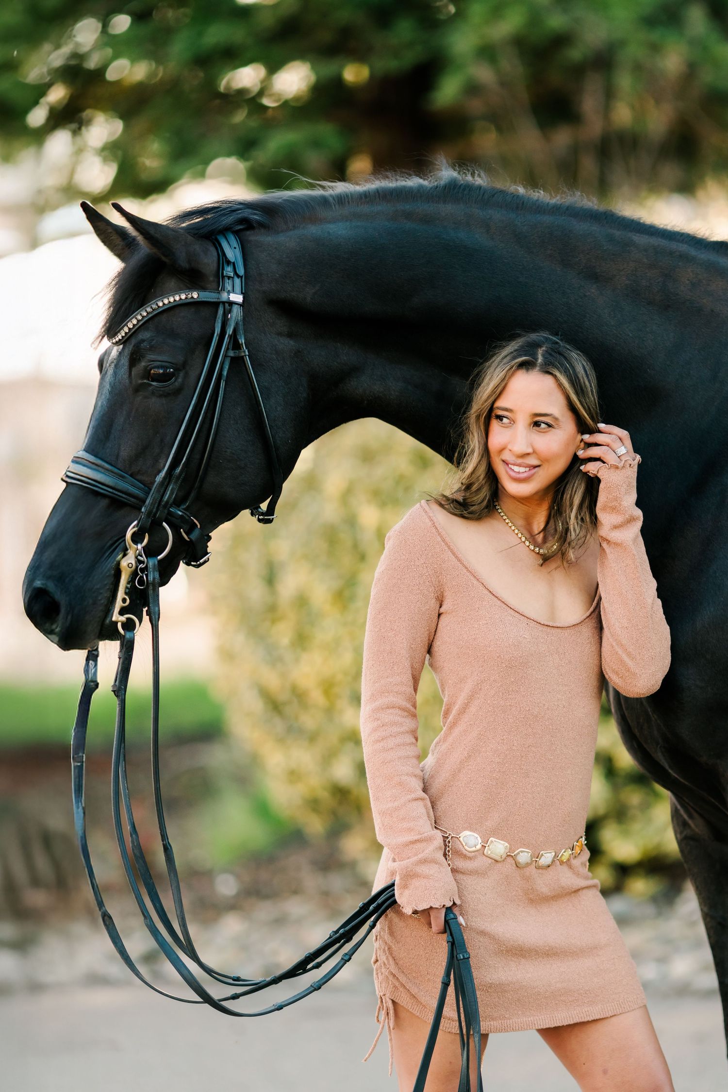 A black horse and someone in a beige sweater pose together in an outdoor photoshoot series.