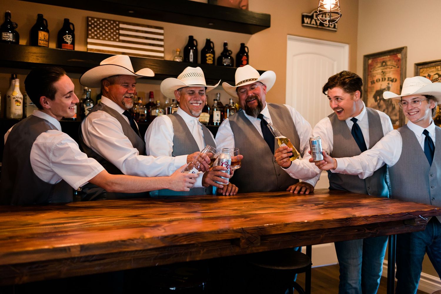 Group of people in western attire gathered around a rustic wooden bar during a celebration.