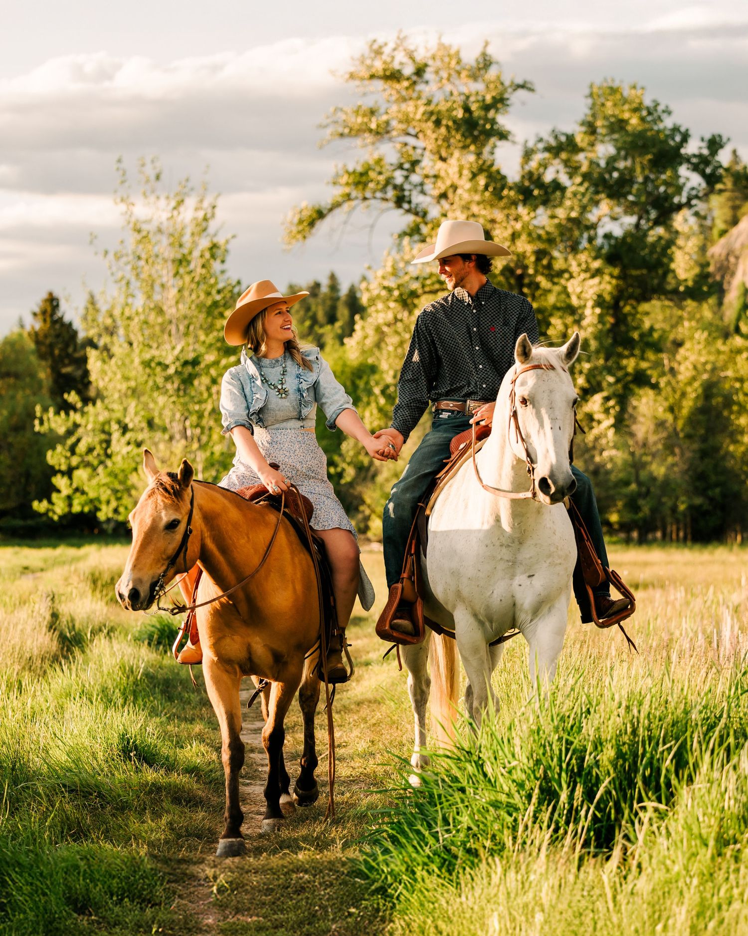 Riders on horseback traverse a sunlit meadow trail during golden hour at sunset.
