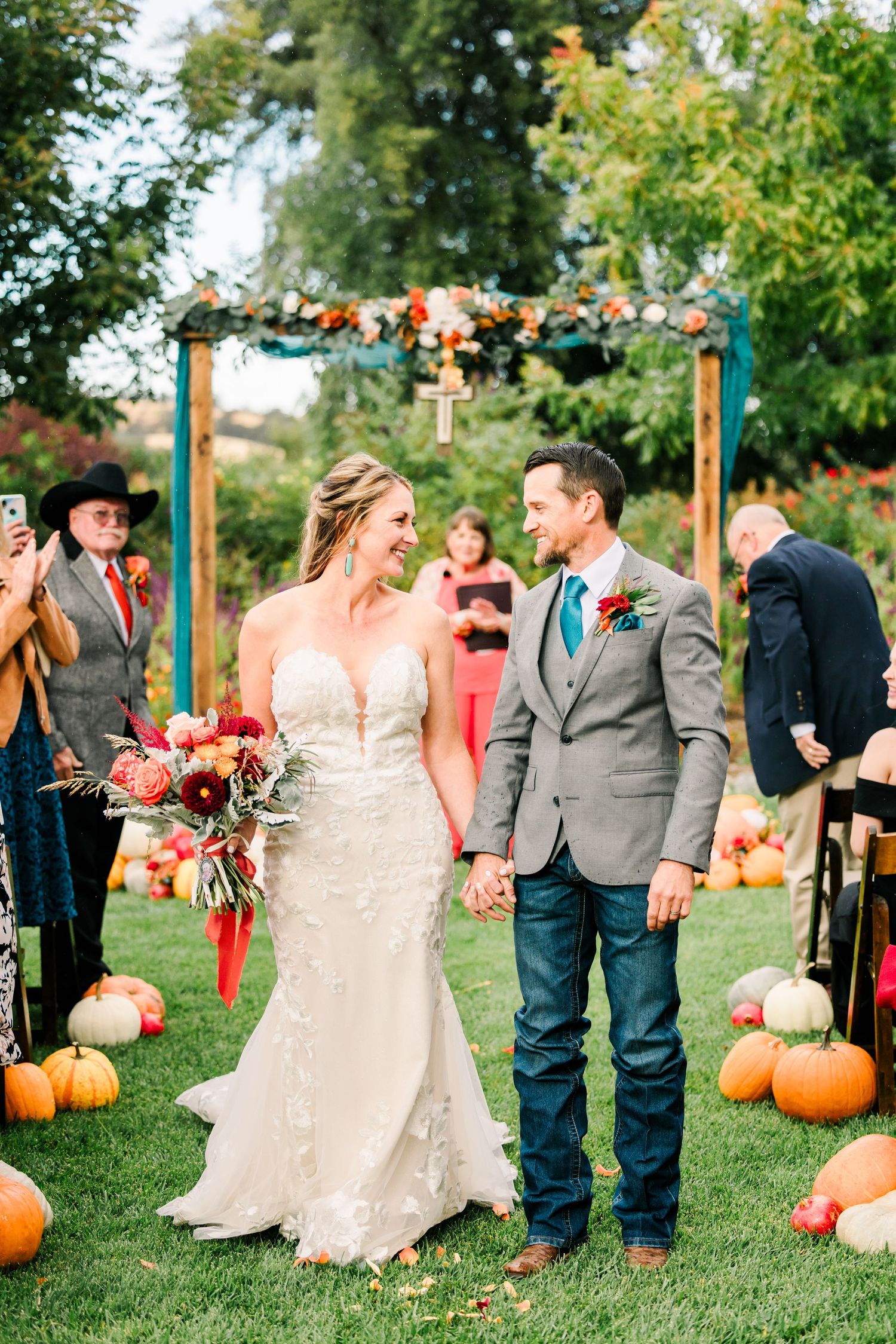 A fall wedding celebration decorated with orange pumpkins and colorful flowers in a garden setting.