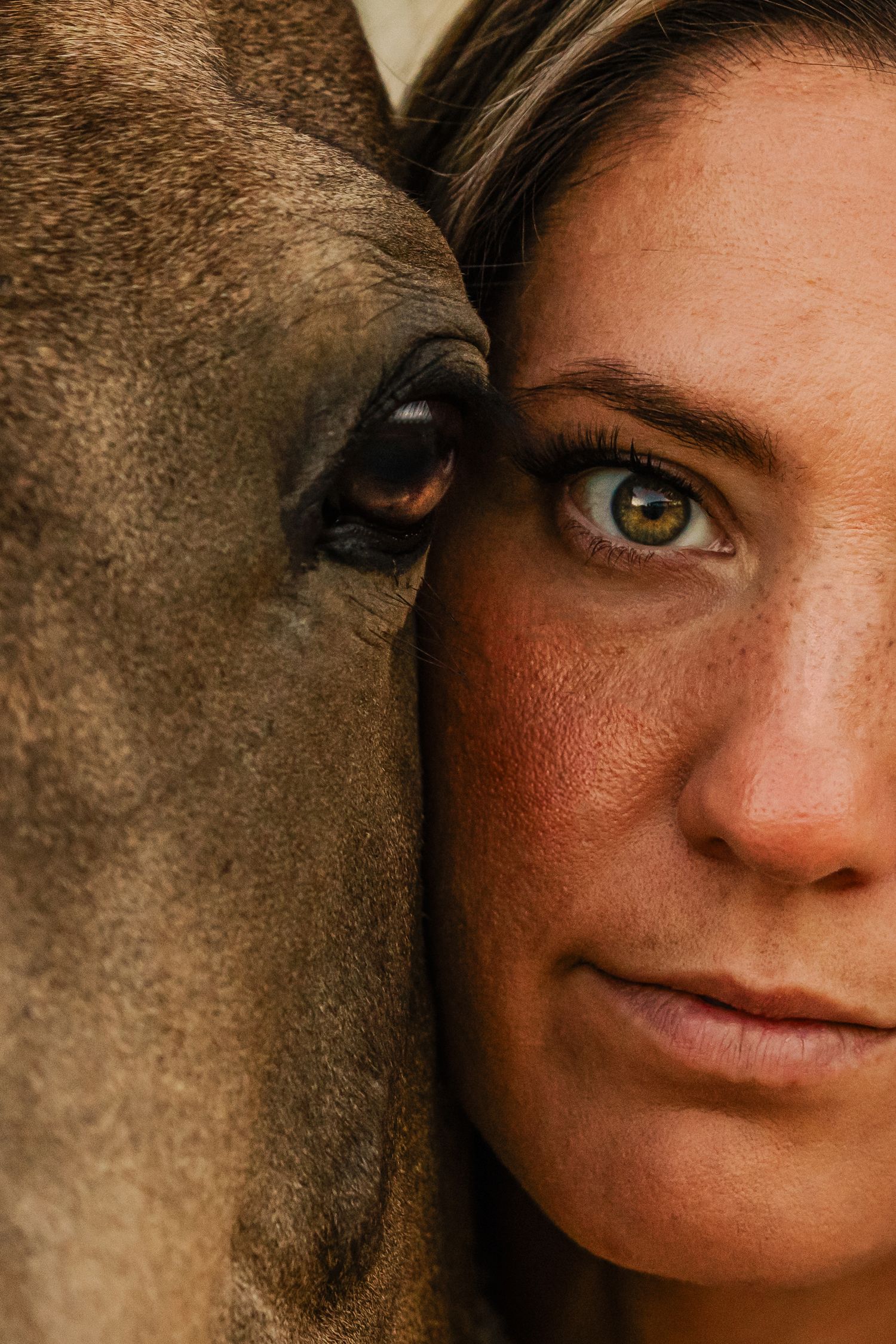 A close-up artistic portrait showing a partial view of bright blue eyes and freckled skin against a dark background.