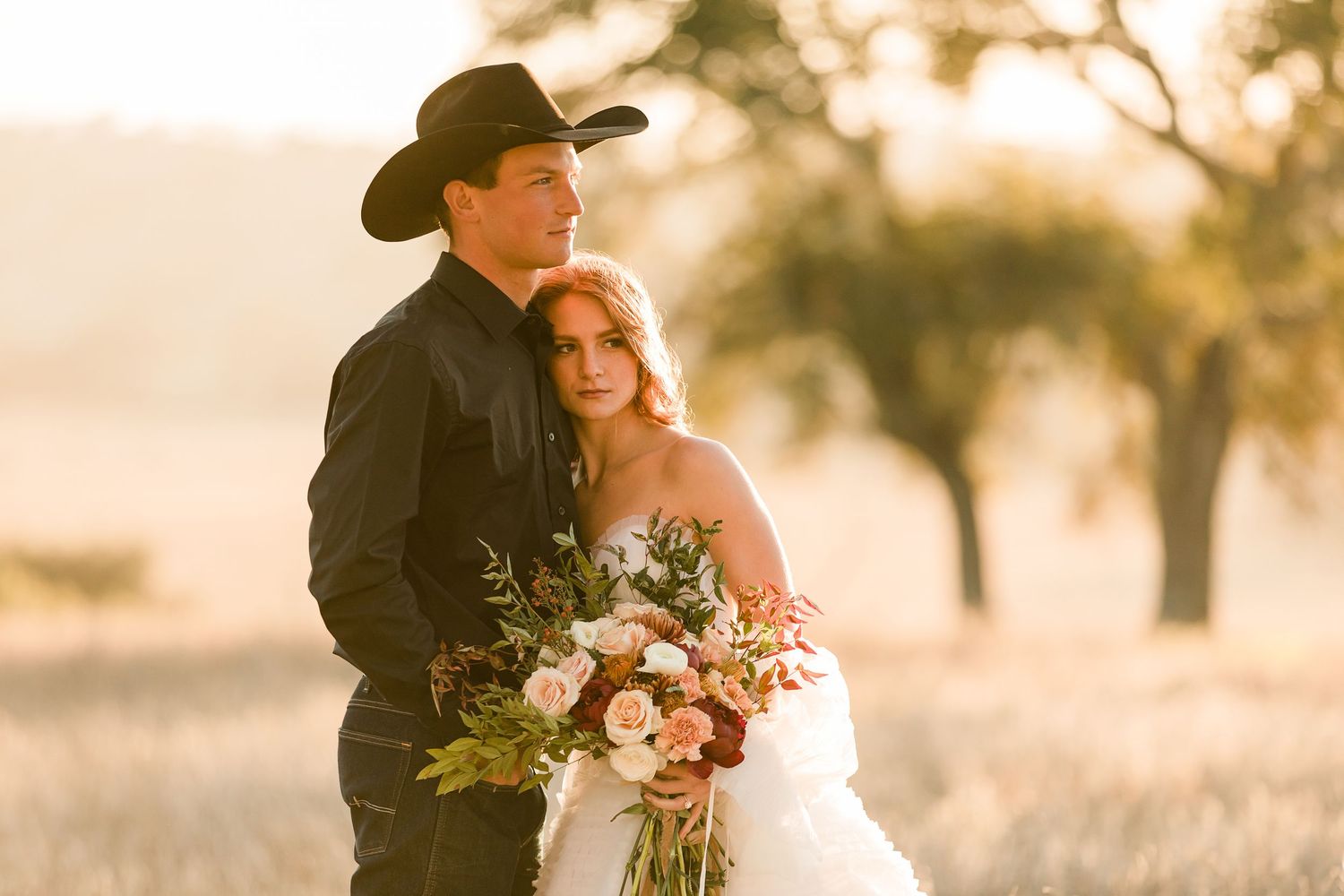 Rustic wedding scene with cowboy hat in warm evening sunlight capturing intimate moments.