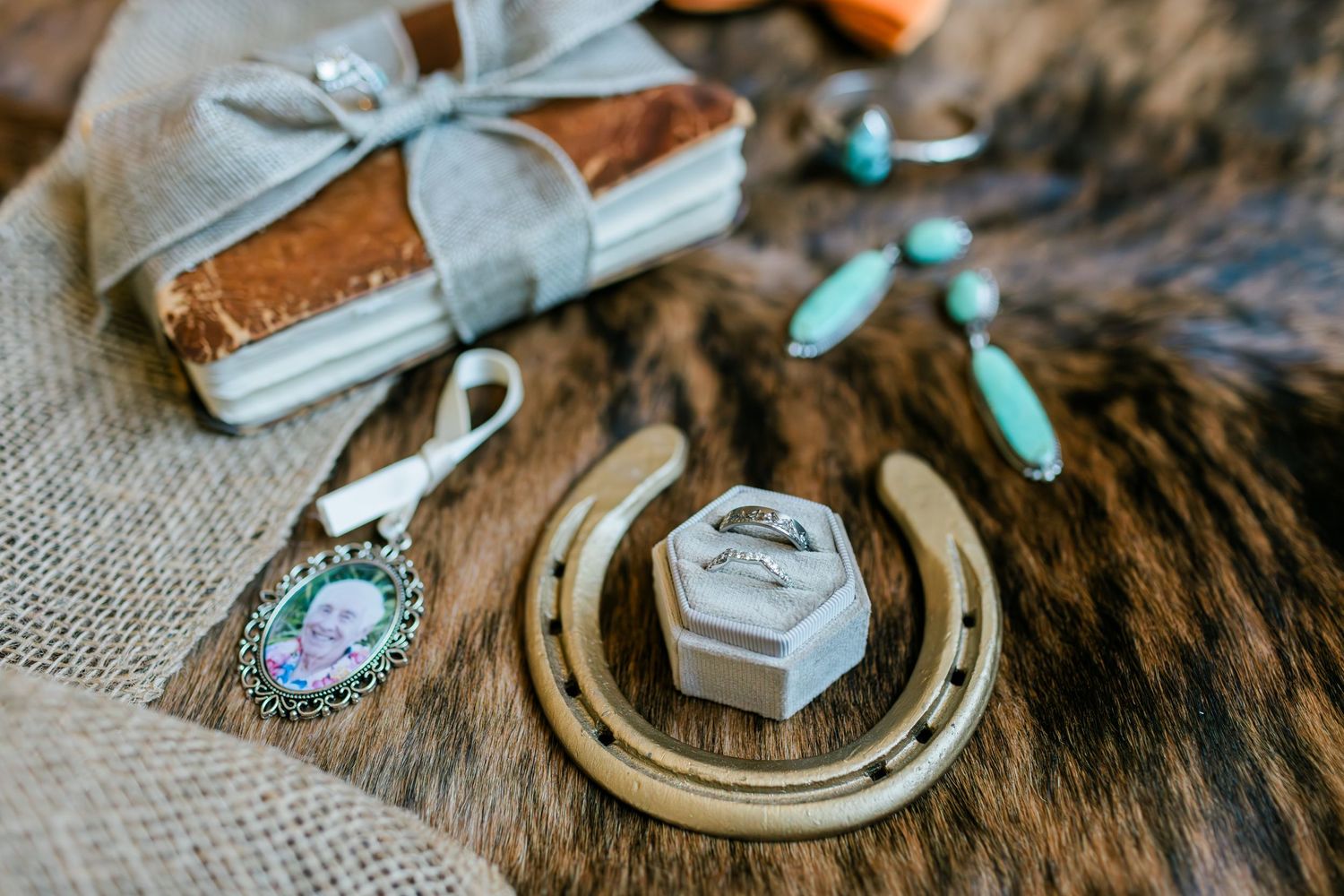 Artisan handmade jewelry and rustic decorative items arranged on vintage wooden surface with fur texture and soft lighting.