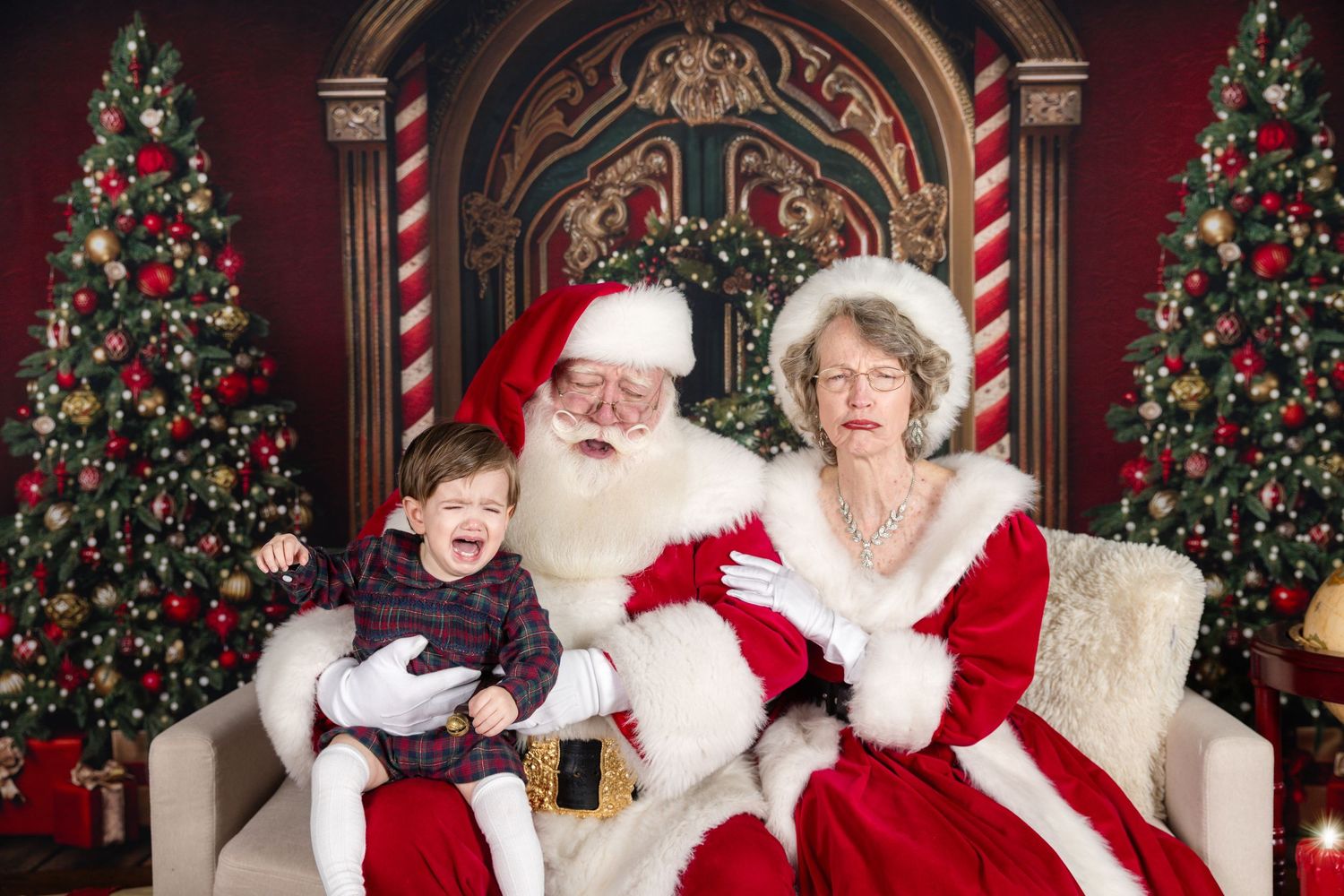 A festive holiday scene with decorated Christmas trees and traditional holiday figures sitting on a white sofa.
