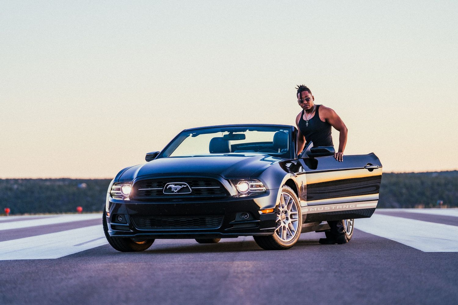 Black Ford Mustang sports car shown in multiple dynamic angles on a road during sunset.