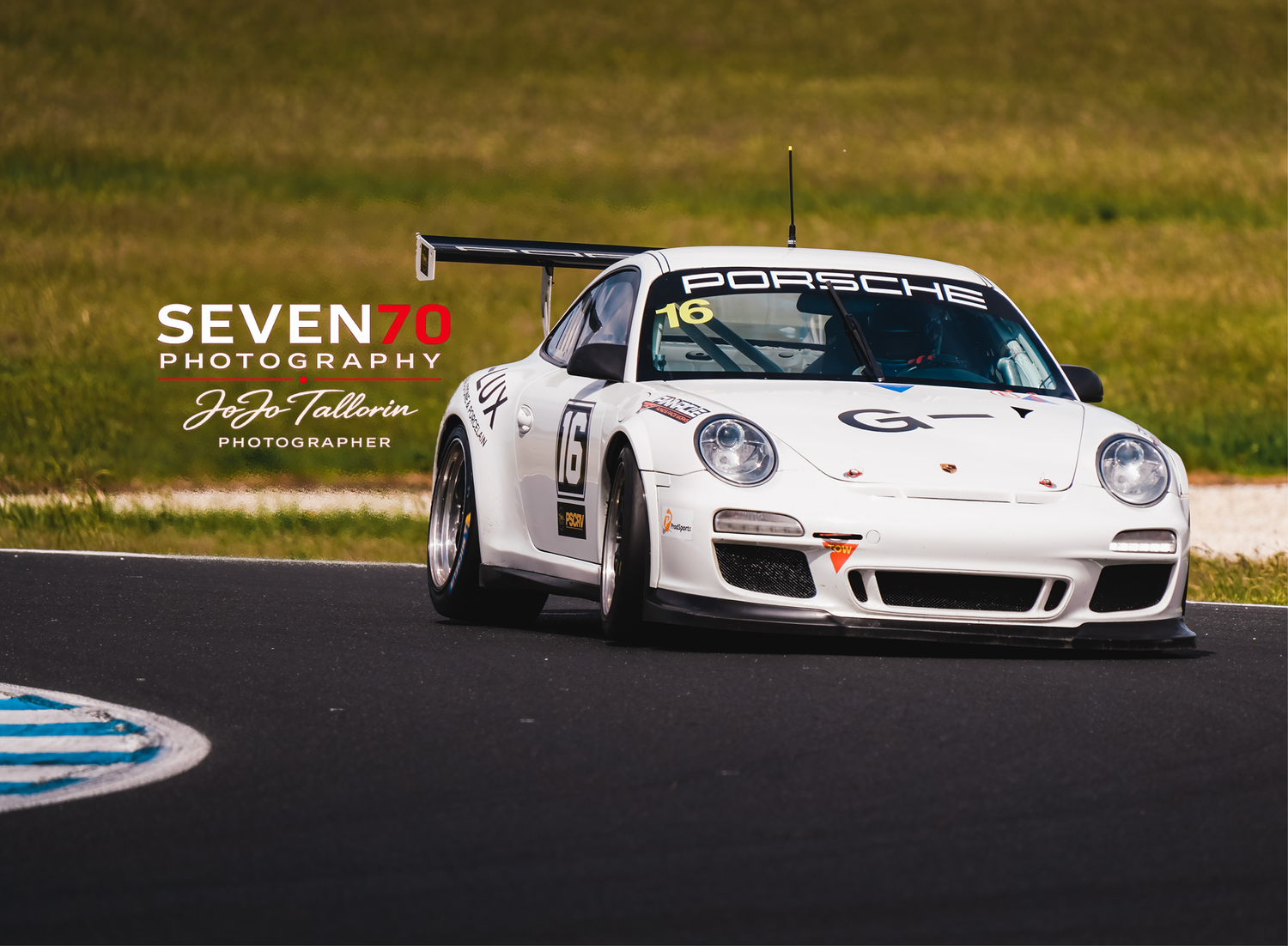 White Porsche 911 GT3 number 16 race car captured at speed on a professional racing circuit.