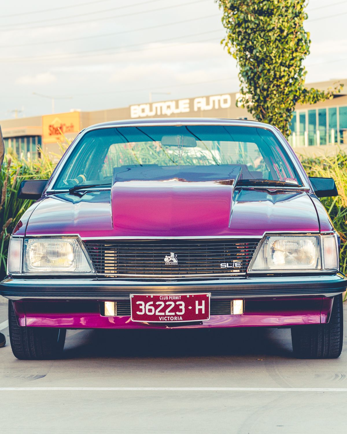 Front view of a purple and pink custom Holden with Victoria license plate 36223-H parked outside Boutique Auto.