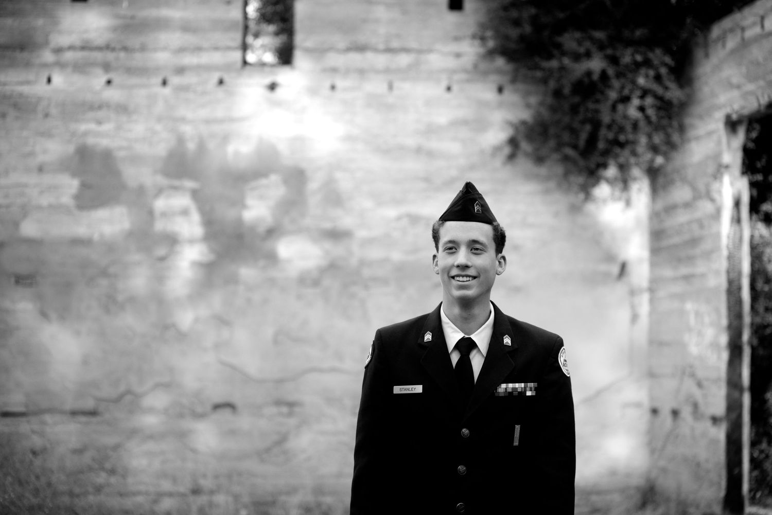 Smiling young man in military dress uniform posing in black and white portrait photo.