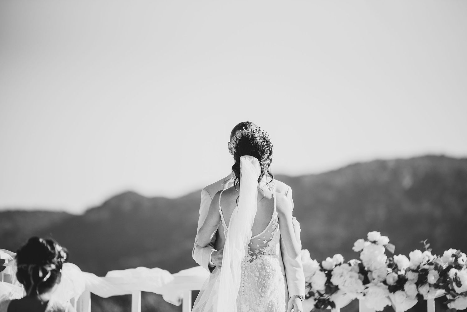 Black and white photo of bride and groom standing back-to-back at an outdoor altar with mountain views.