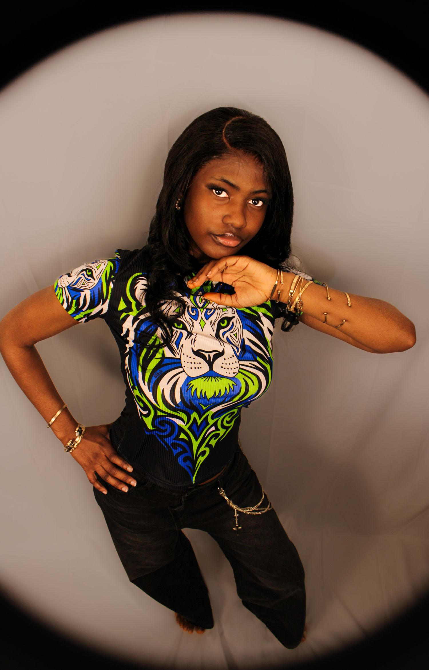 Fish-eye overhead shot of woman in colorful lion graphic shirt posing with hand on chin.