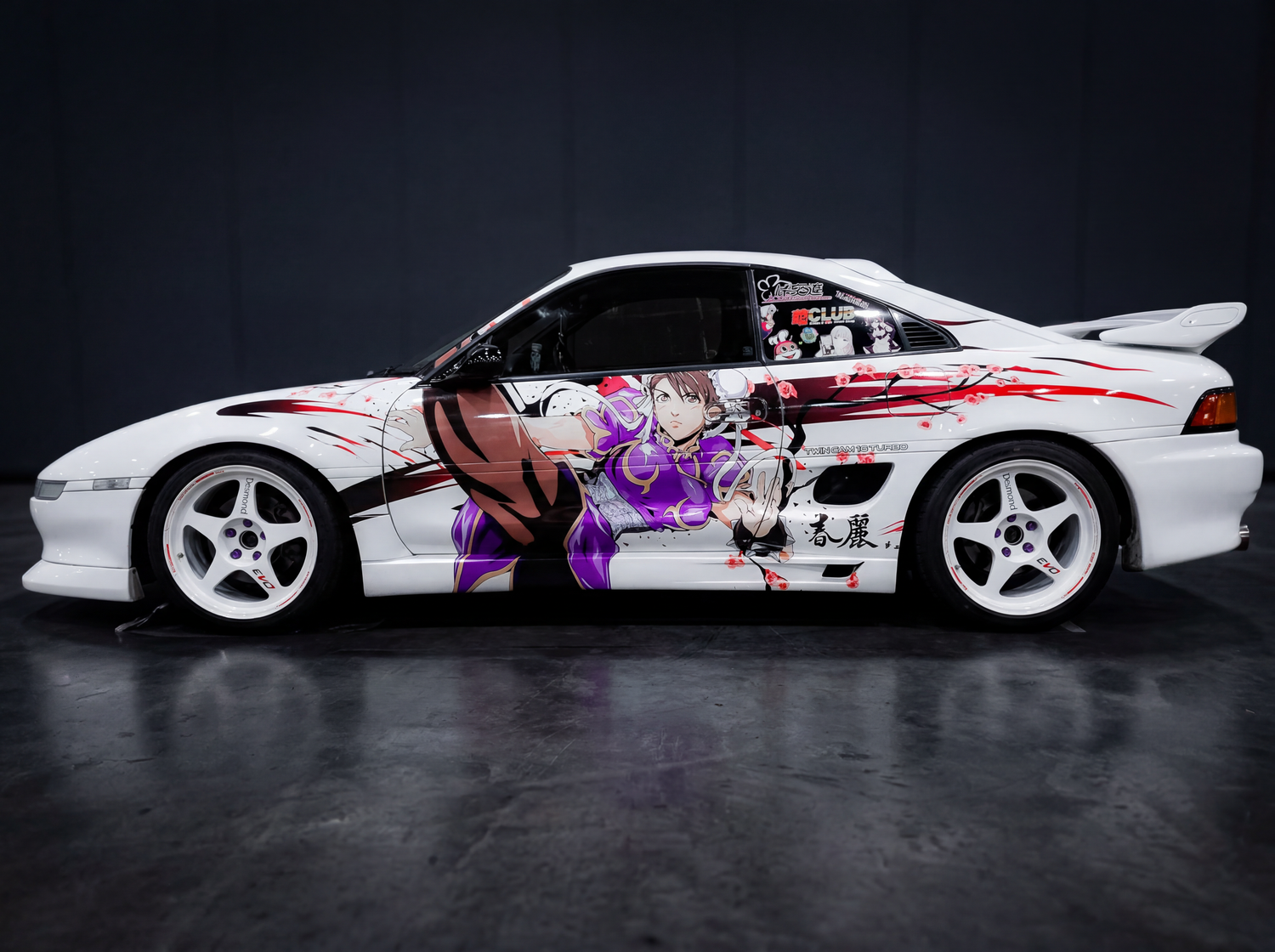 White Toyota AE86 with purple anime character wrap on dark studio background with white rims.