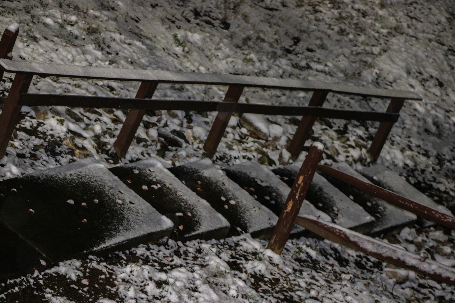 Snow-dusted metal staircase railing outdoors in winter conditions.