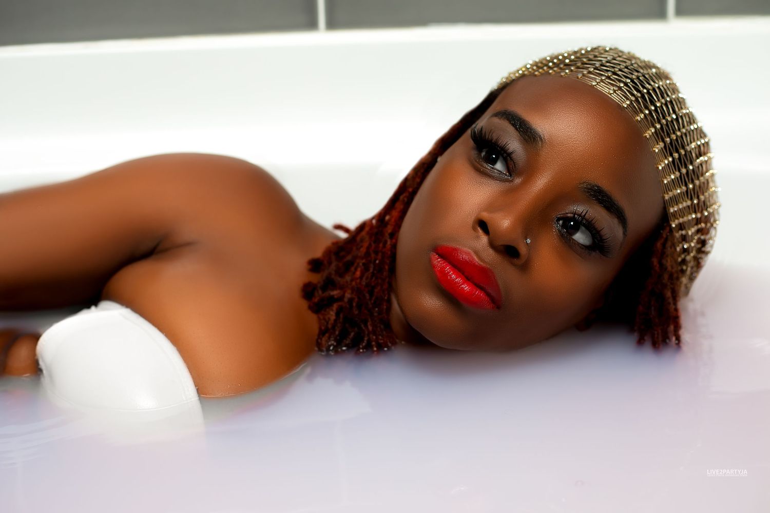 Woman with red braids relaxing in a white milk bath.