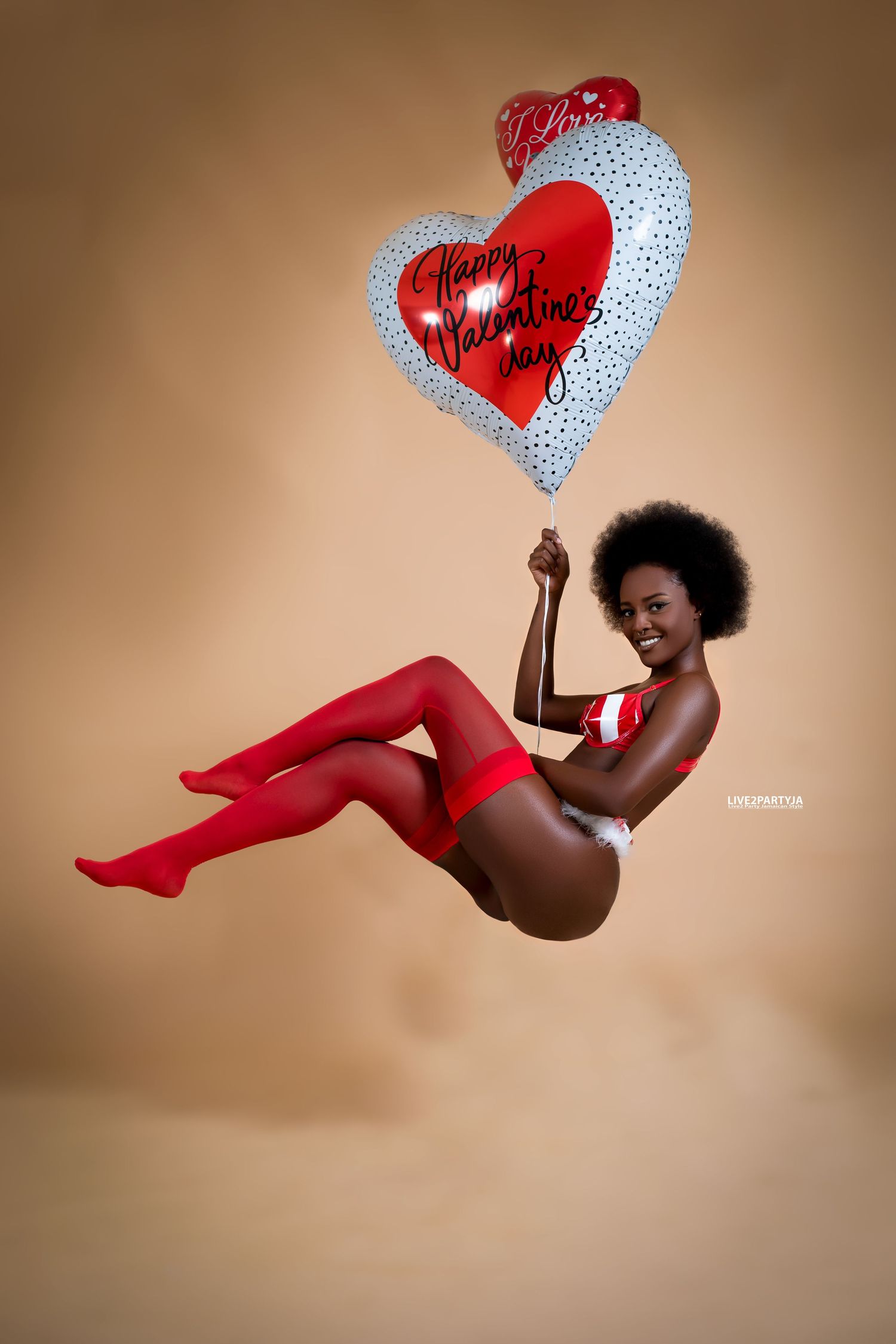 Woman in red lingerie and stockings floating with Happy Valentines Day heart balloon.