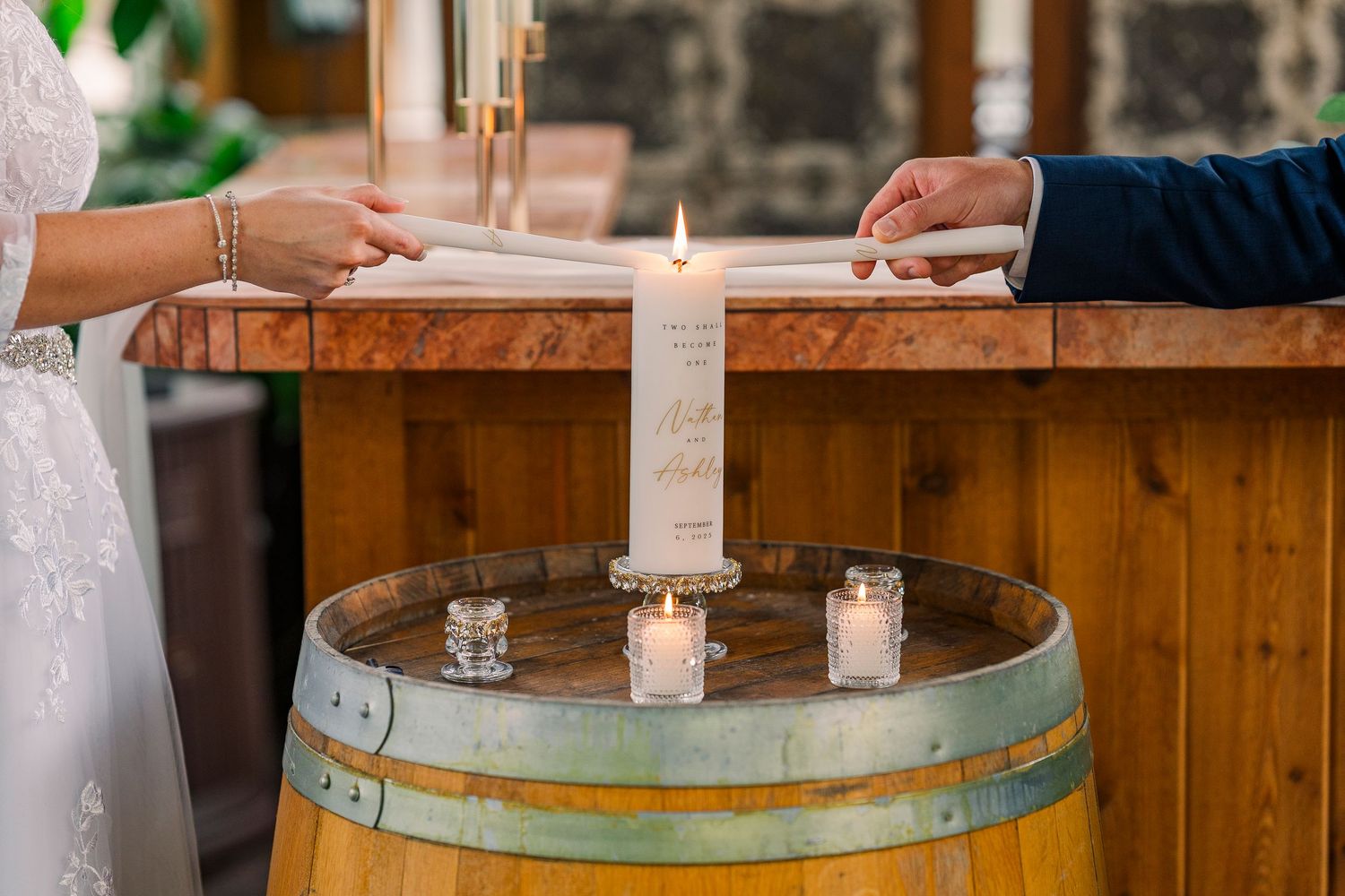 Couple performing a unity candle ceremony on a rustic wine barrel at their wedding in the conservatory at Gervasi Vineyard wedding venue.