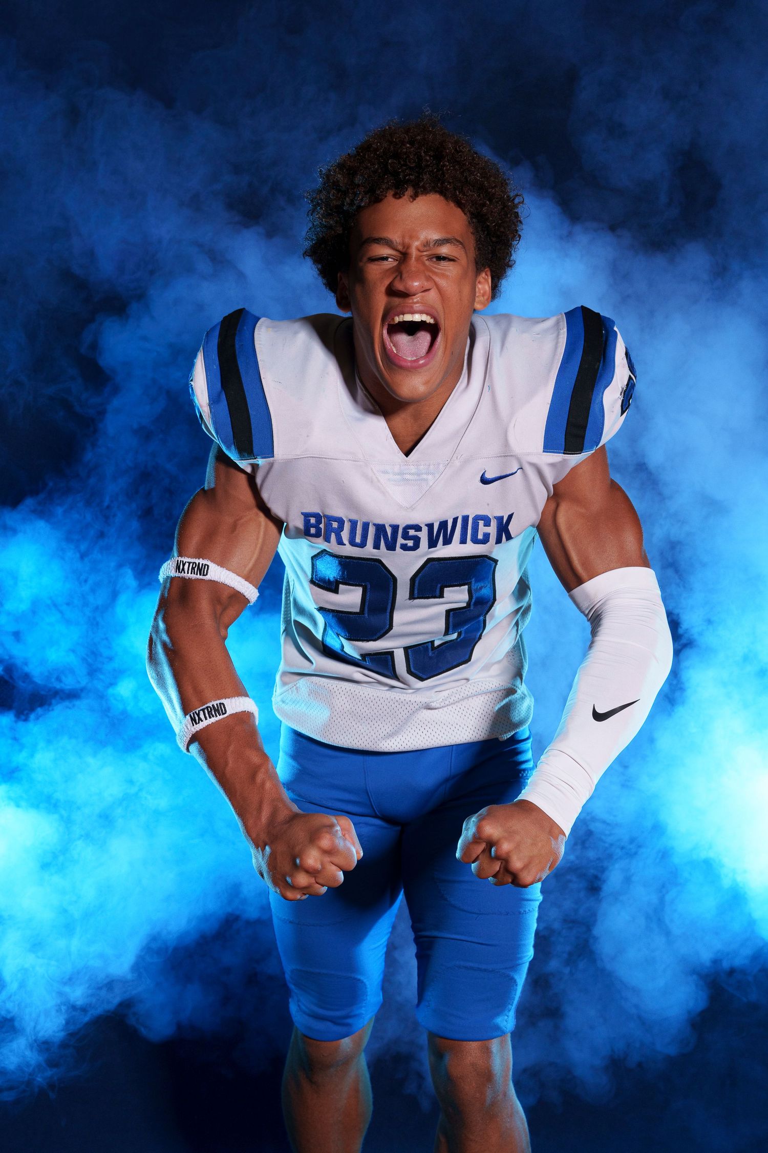 Brunswick football player number 23 posing energetically in blue smoke for team photo.