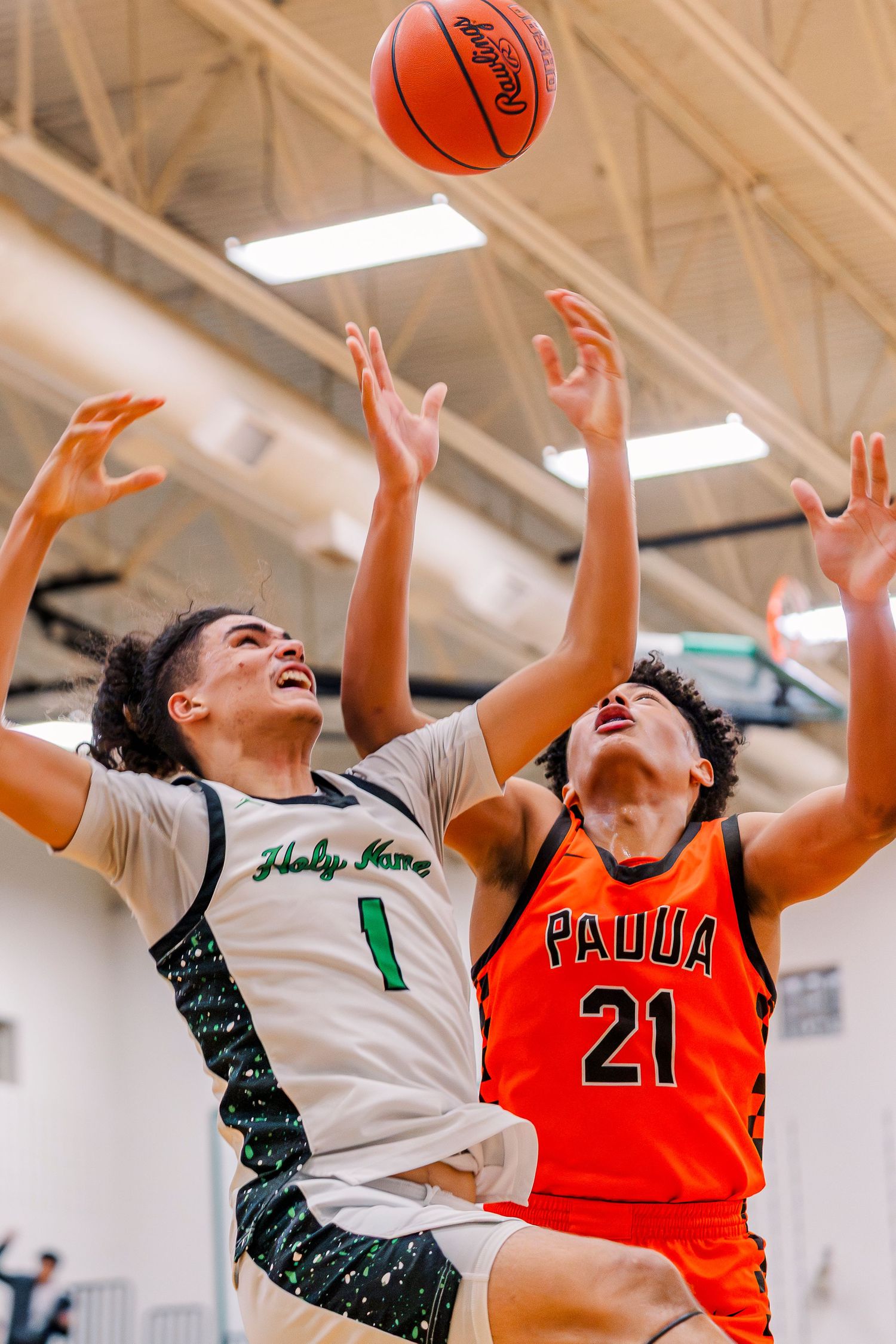 Holy Name #1 and Padua #21 battle for a rebound during an intense high school basketball game indoors.