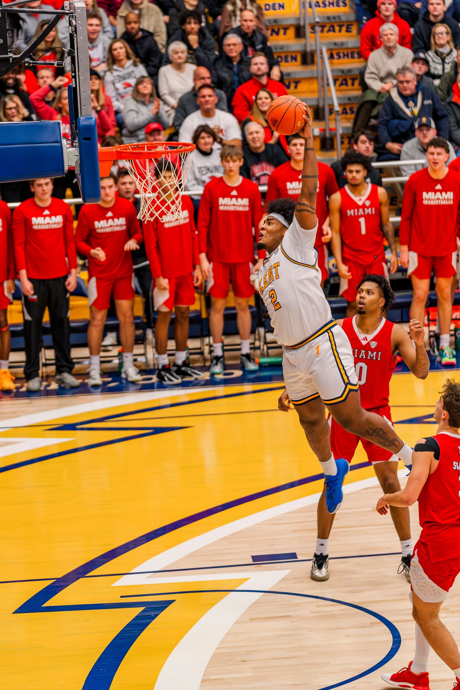 Kent State basketball player jumps for a slam dunk against Miami defenders in red at the MAC center