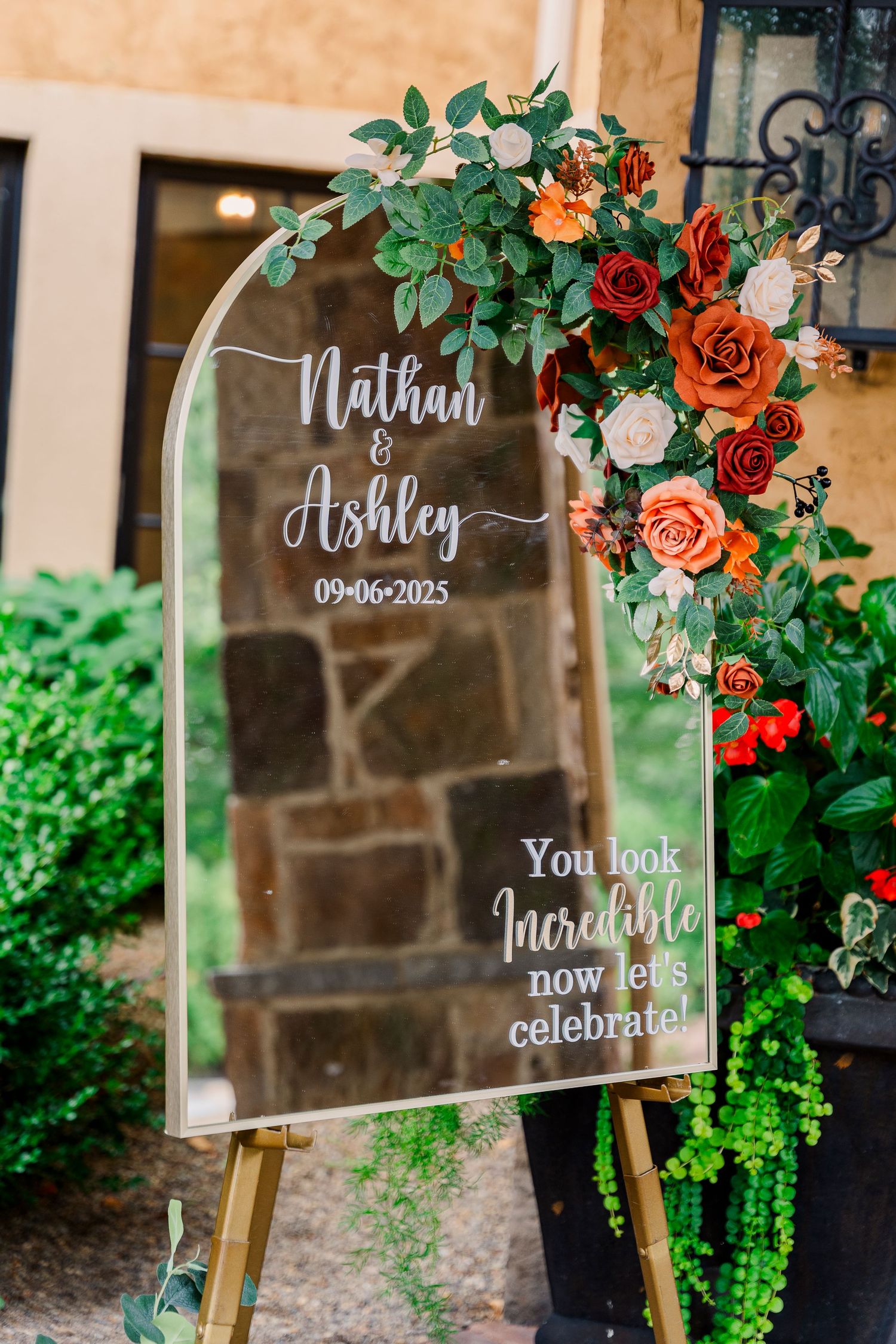 Decorative wedding welcome mirror sign for Nathan and Ashley with floral arrangement.