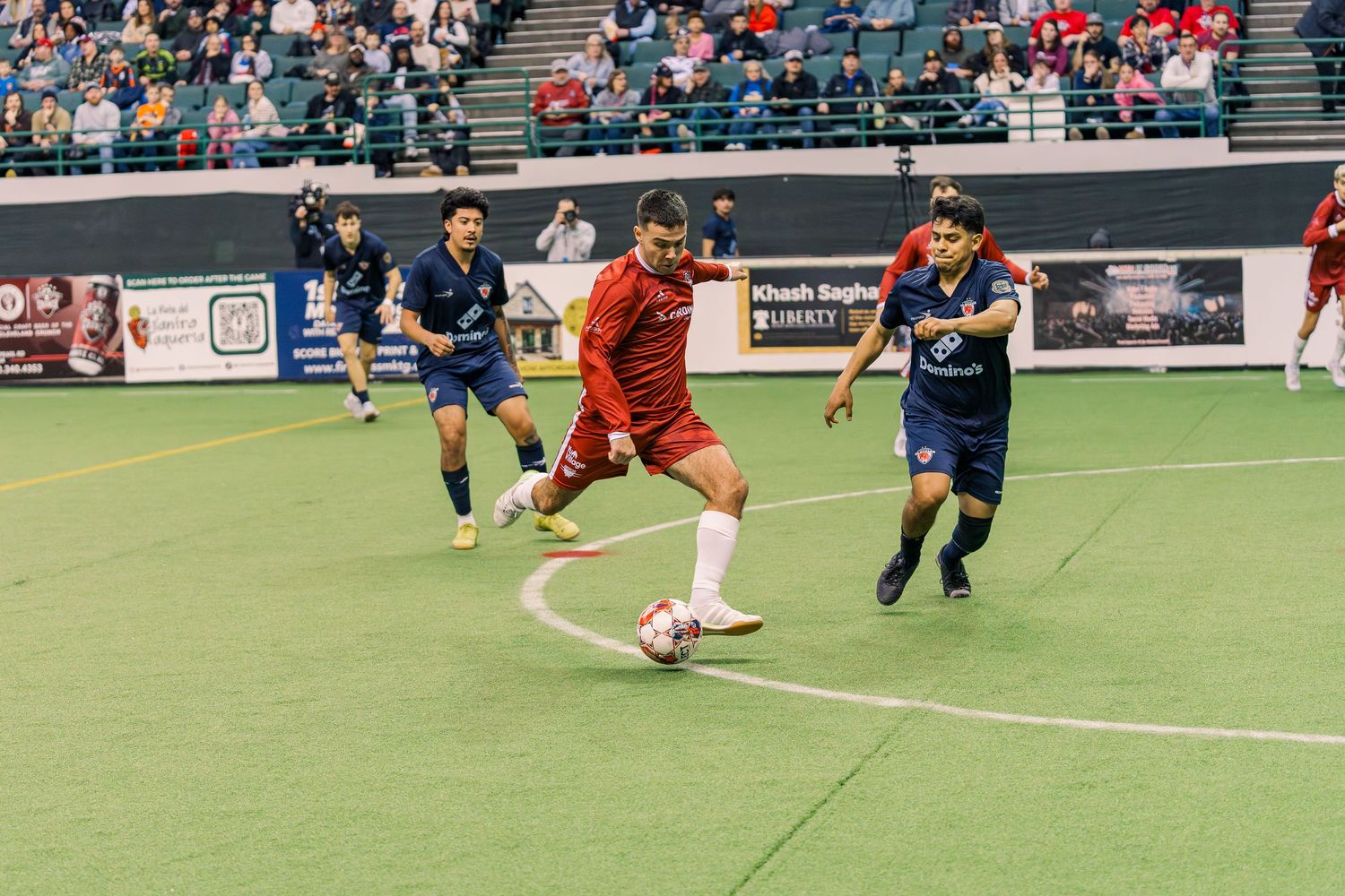 Indoor soccer players compete on turf field during intense futsal match in packed arena. Cleveland Crunch game.