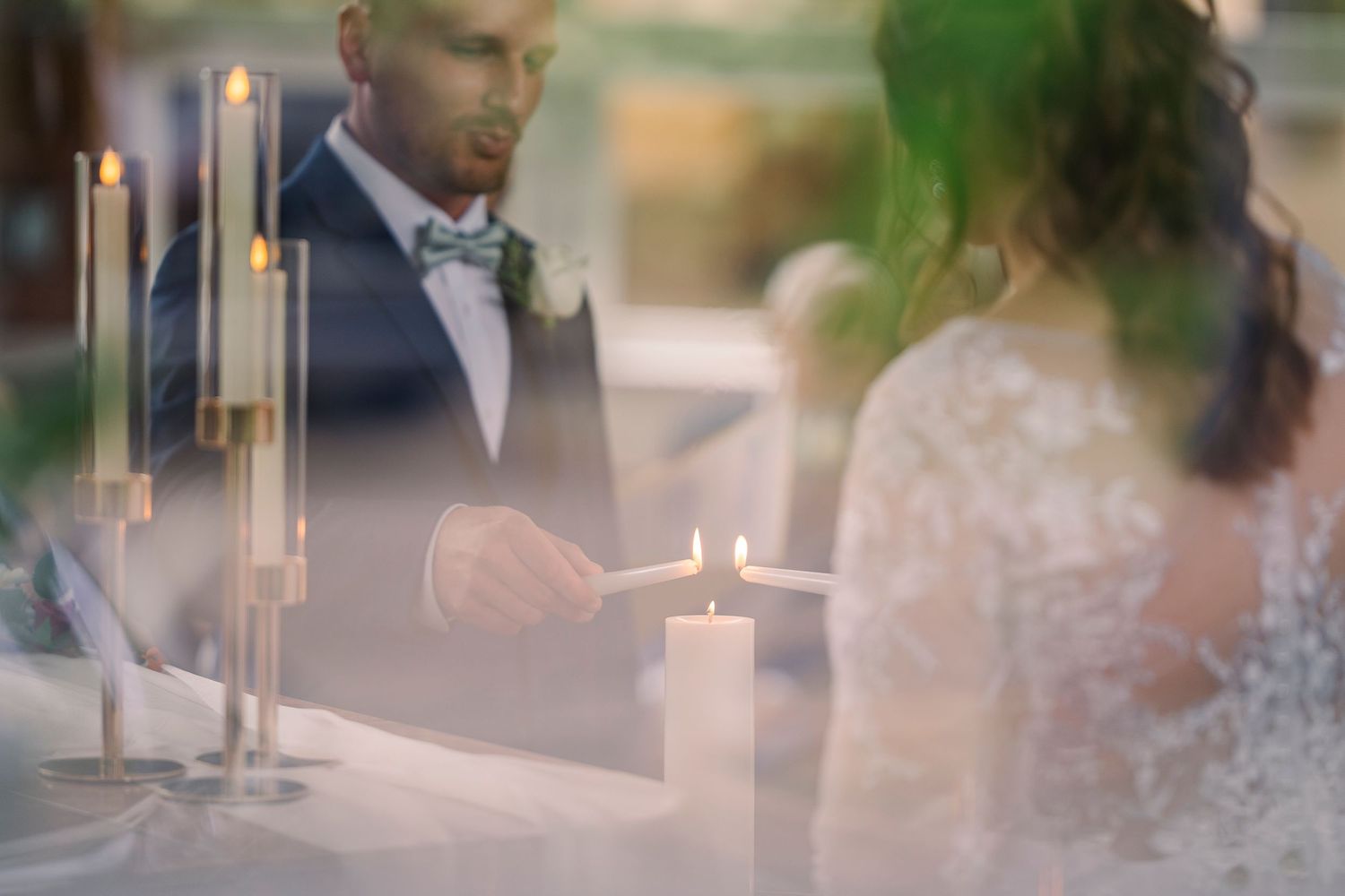 Bride and groom lighting a unity candle together at their elegant wedding reception.
