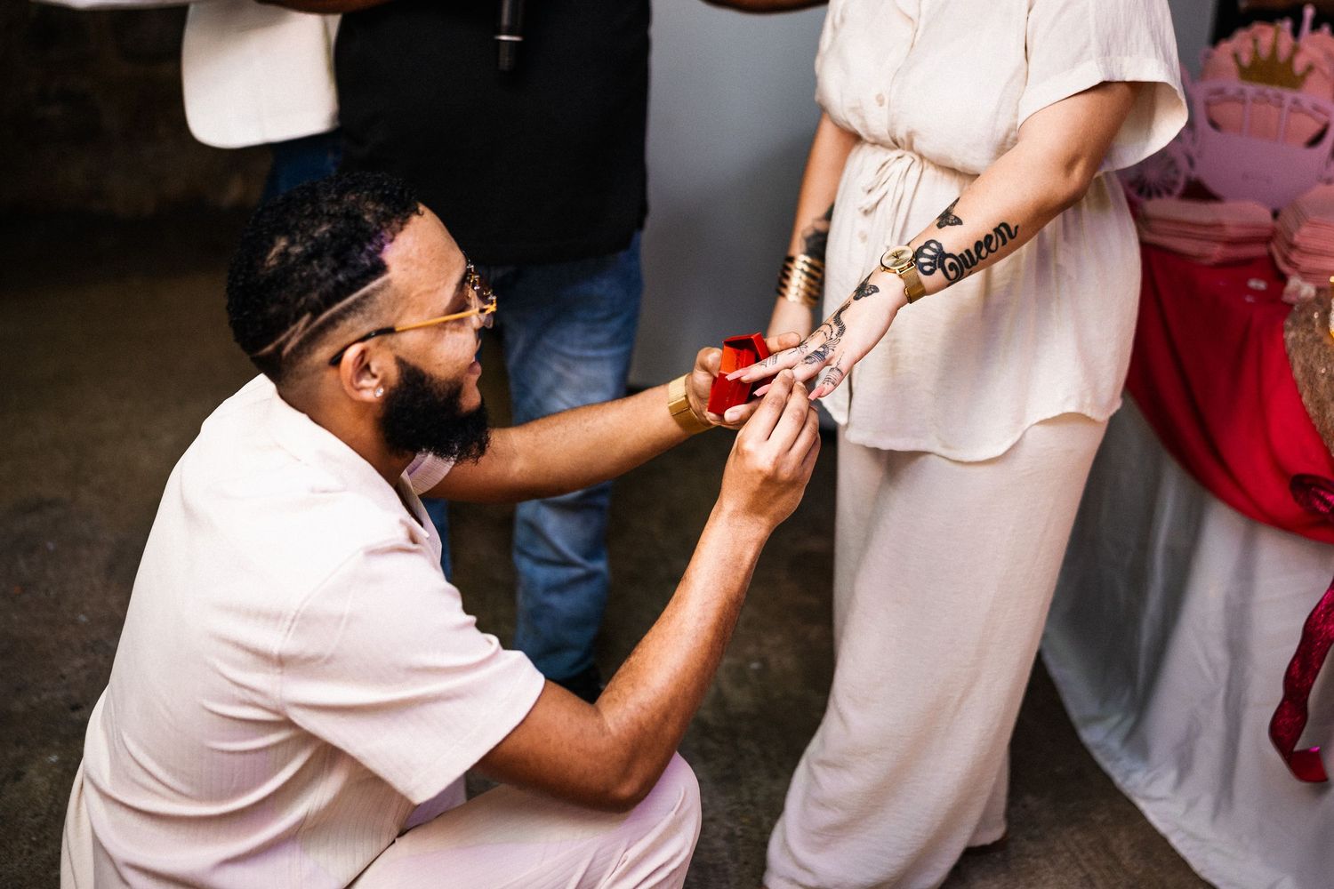 Man kneeling to place a ring on a woman's decorated hand during a special ceremony.