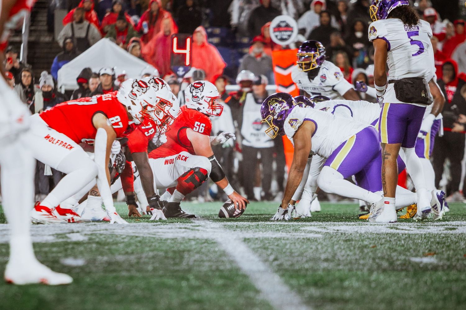 NC State Wolfpack offense lines up against East Carolina Pirates defense during intense night bowl game.