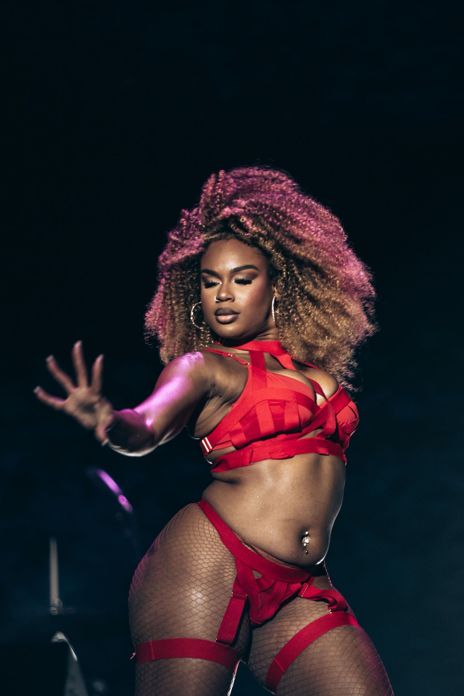 Female dancer in red lingerie performing on stage under lights.