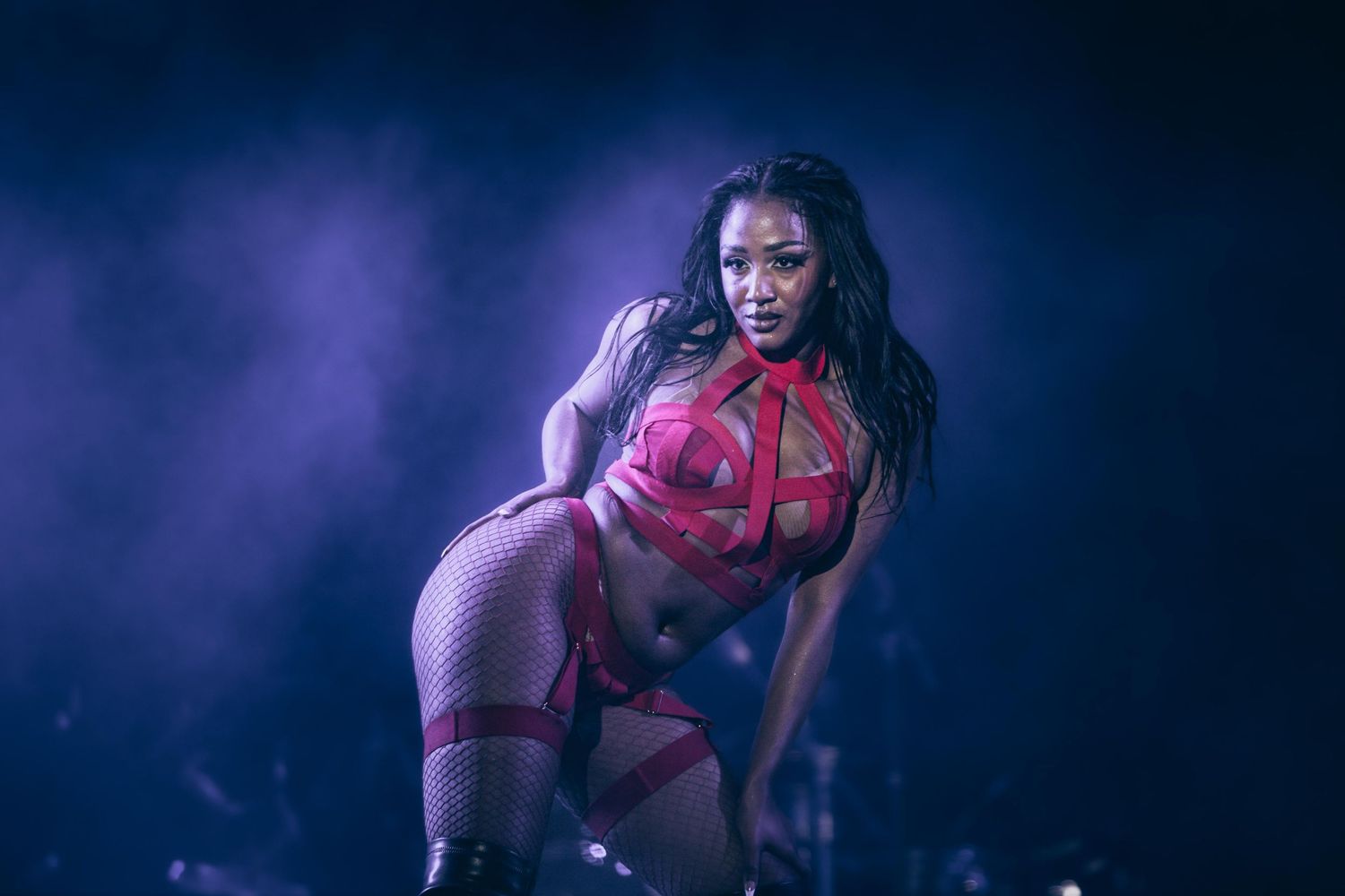 Female performer in red outfit dancing on smoky stage.