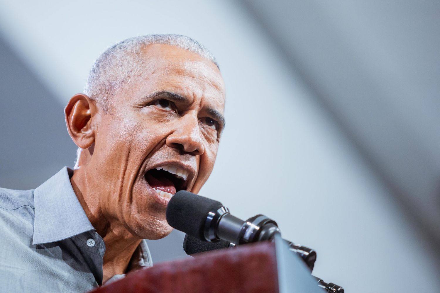 A man speaks passionately into a microphone at an outdoor podium event.
