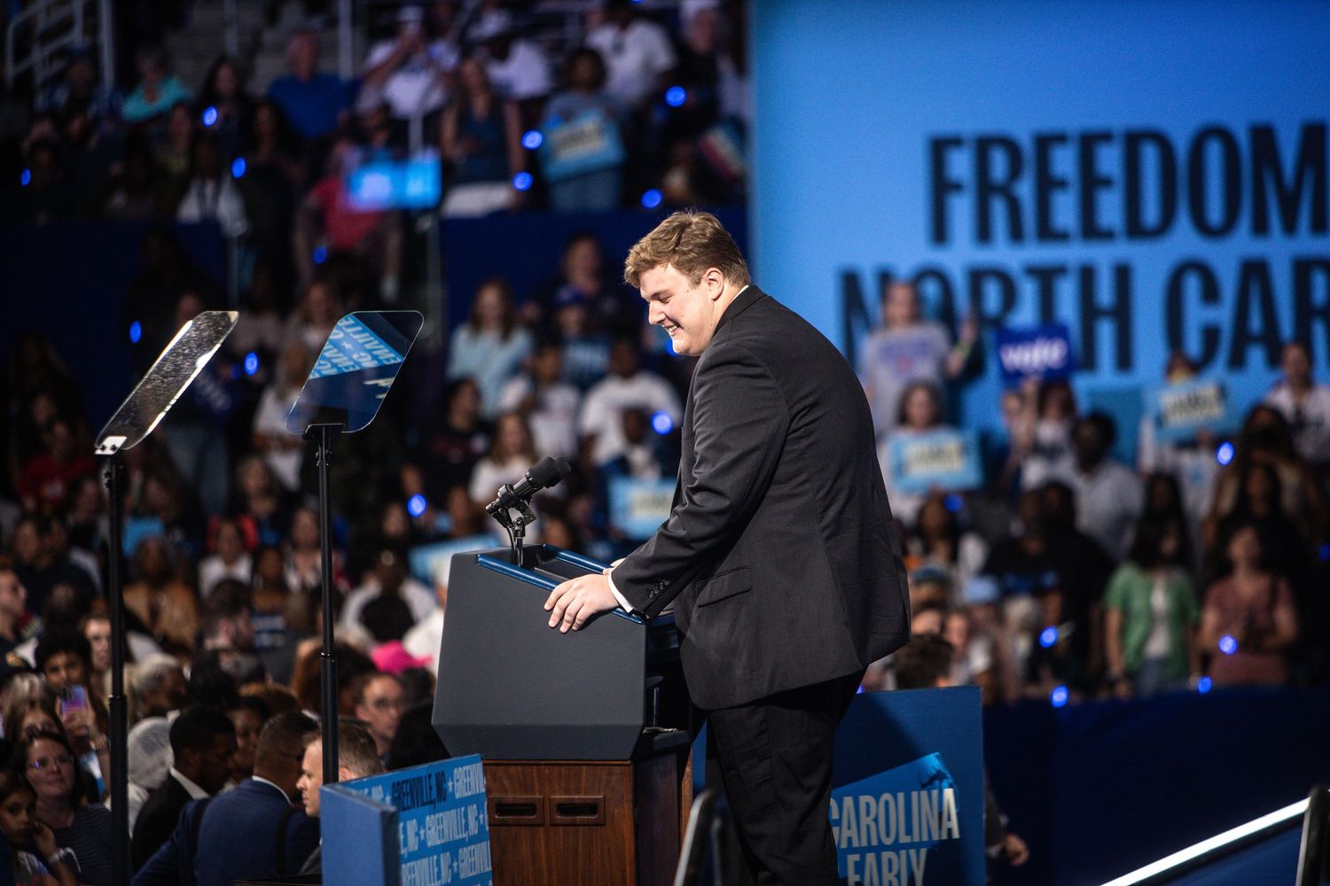 A man in a black suit speaks at a podium during a Freedom for North Carolina political rally.