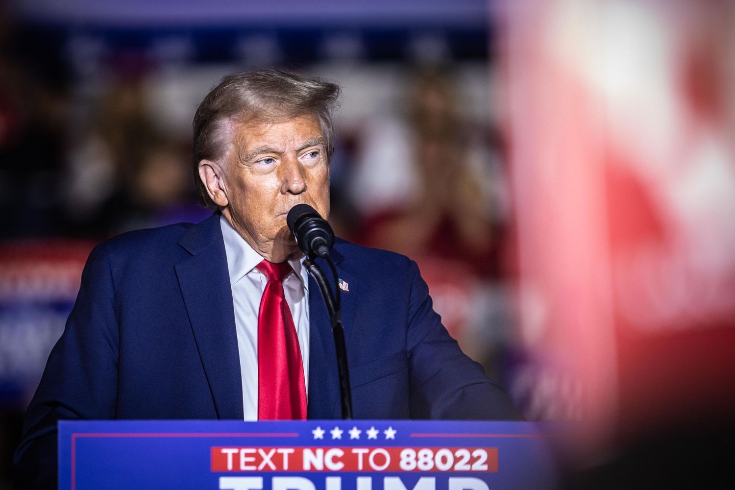 Donald Trump speaks at a microphone at a North Carolina campaign rally with a Trump Vance podium sign.
