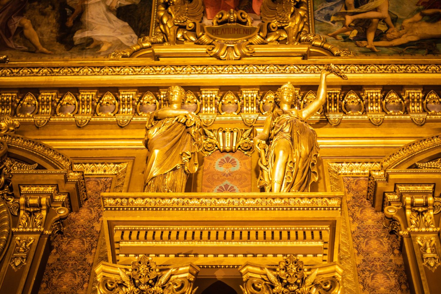 Gilded gold sculptures and ornate decorative carvings on the wall of the Paris Opera Garnier.