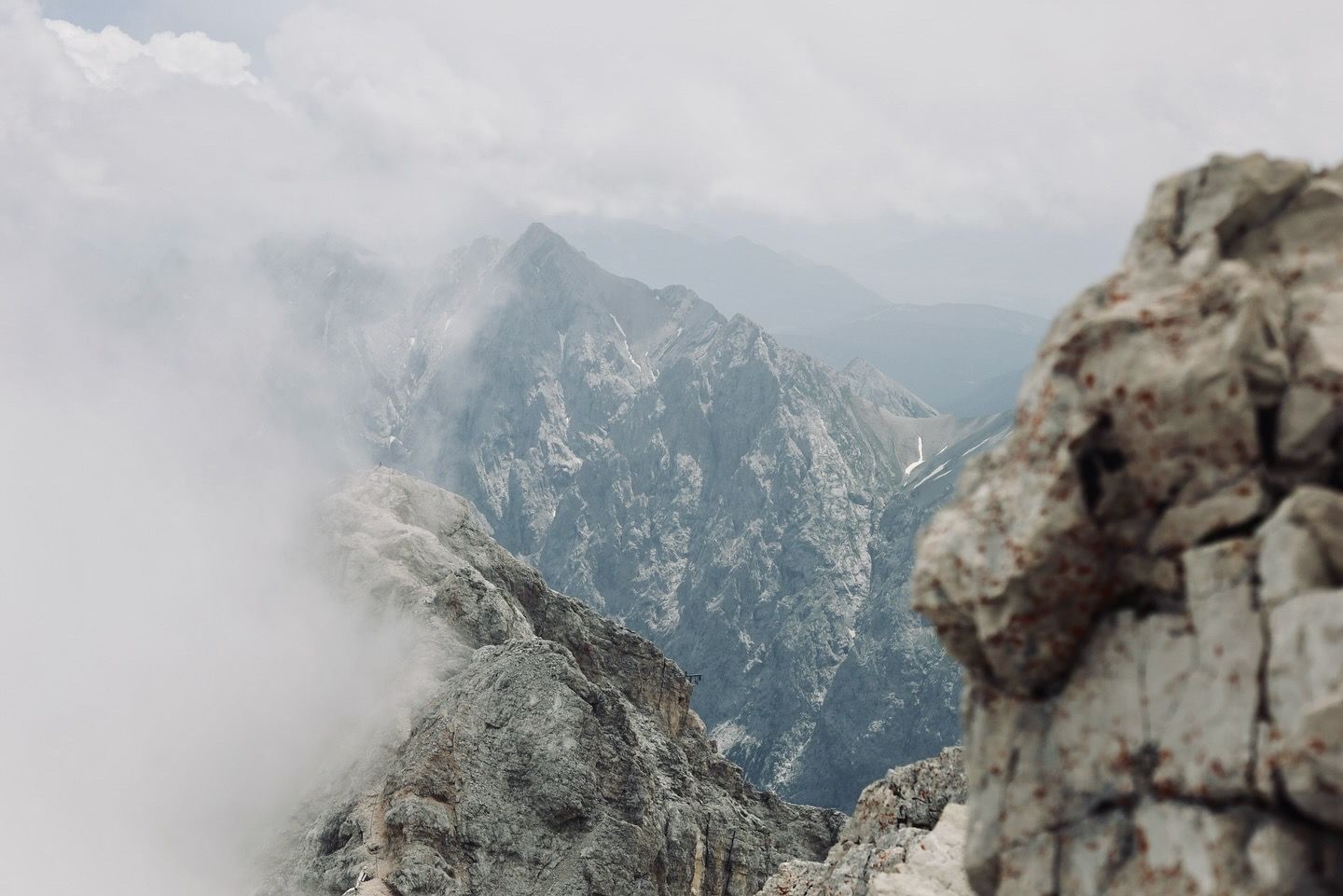 Dramatic misty mountain peaks viewed from a high rocky vantage point in the Alps.