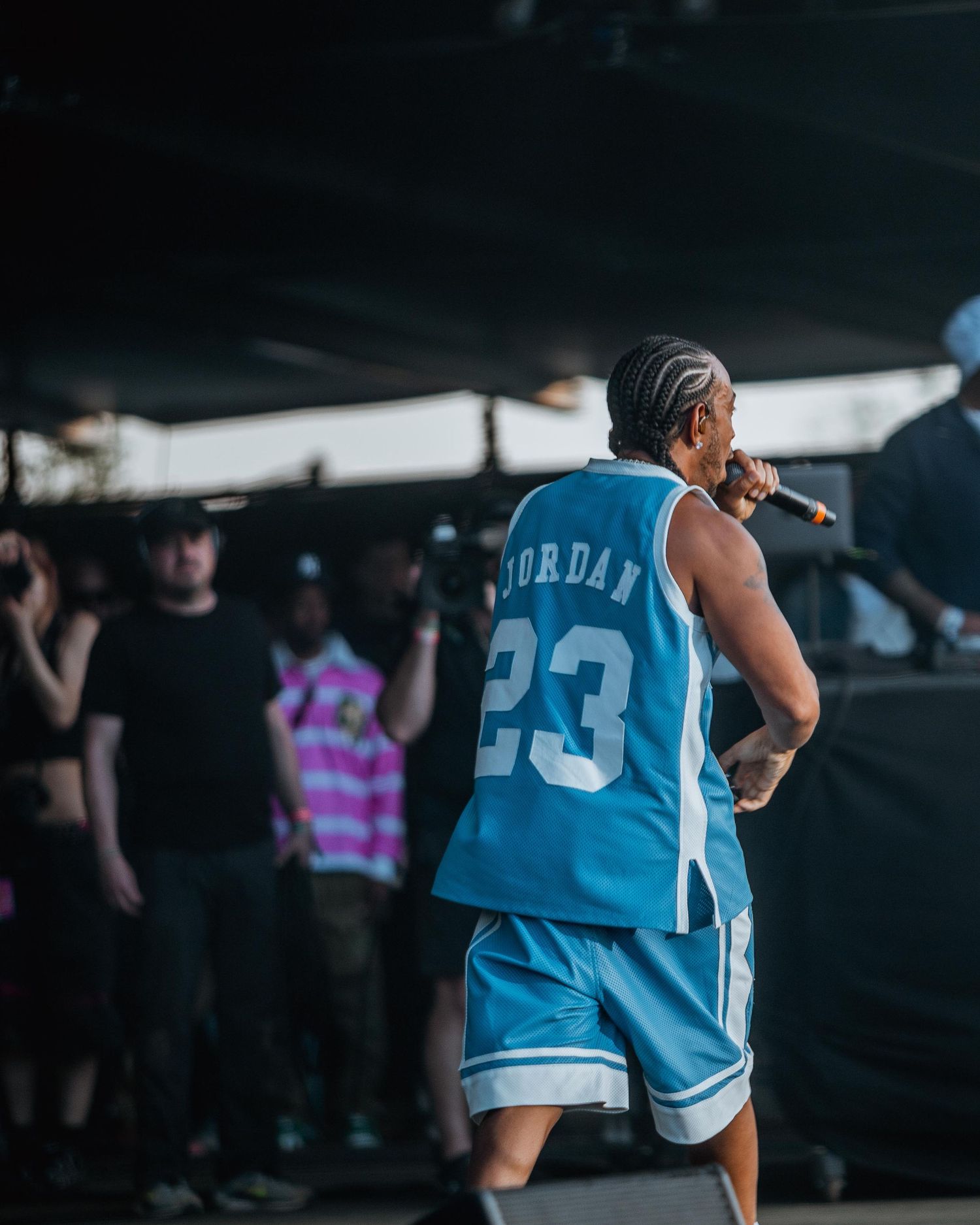 Back view of performer in Jordan 23 jersey on outdoor stage.