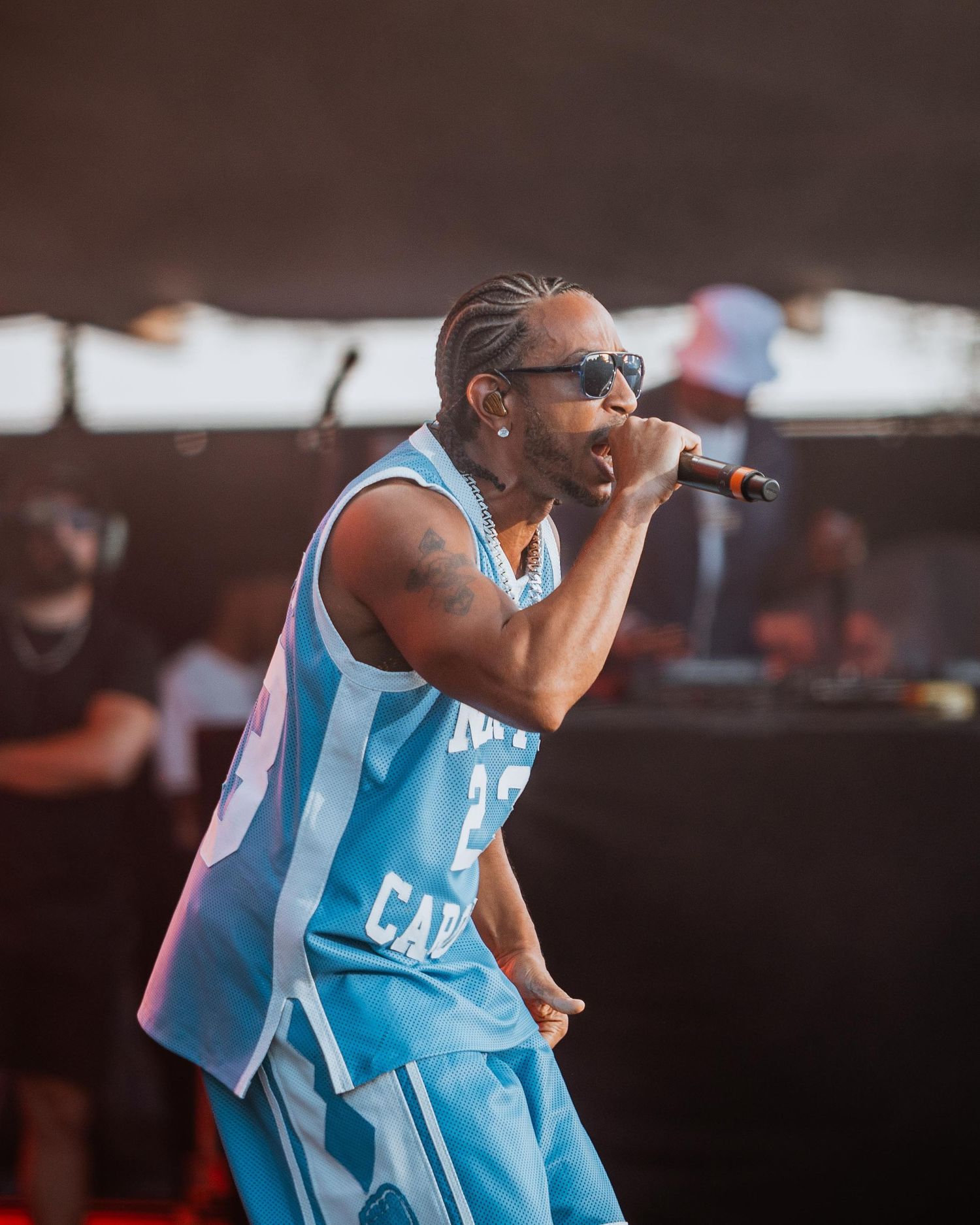 Male rapper in light blue Carolina jersey performing on stage.