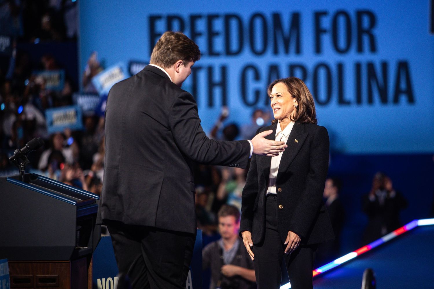 Kamala Harris and a male speaker interact on stage at a Freedom for North Carolina campaign rally.