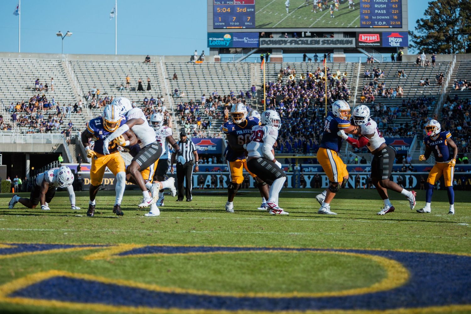 ECU Pirates quarterback scrambles under pressure during college football game at Dowdy-Ficklen Stadium.