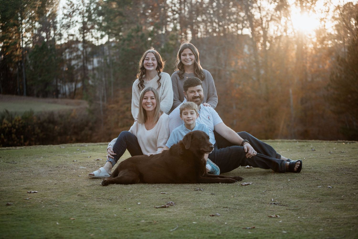 Happy family with dog posing at golden sunset in autumn park with four children and parents.