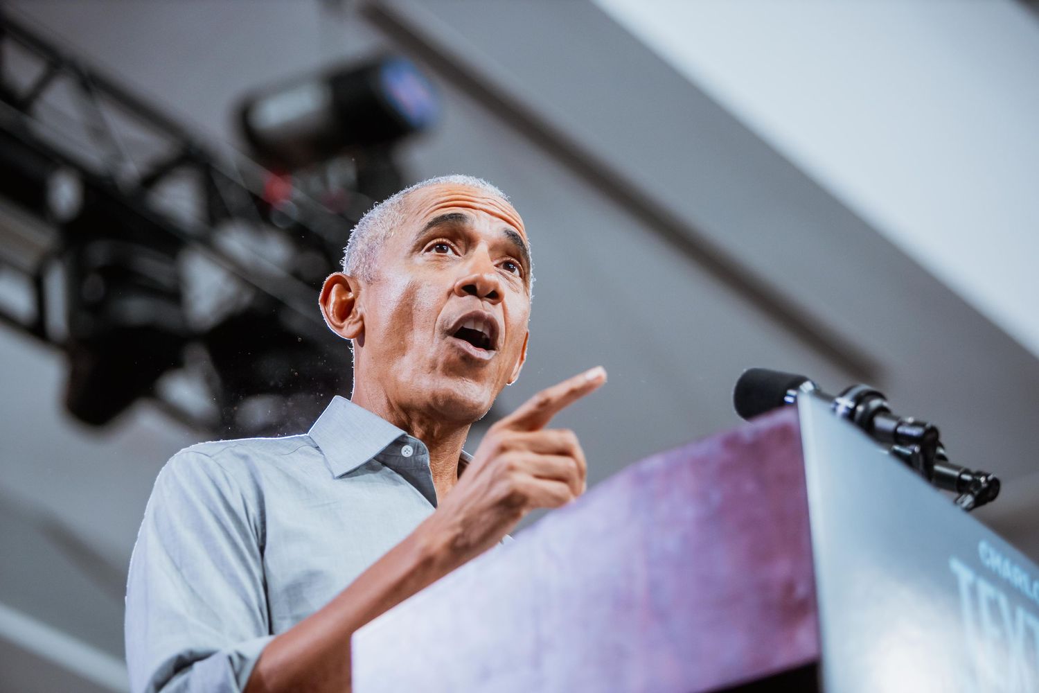 A man gestures while speaking passionately at an outdoor podium event.