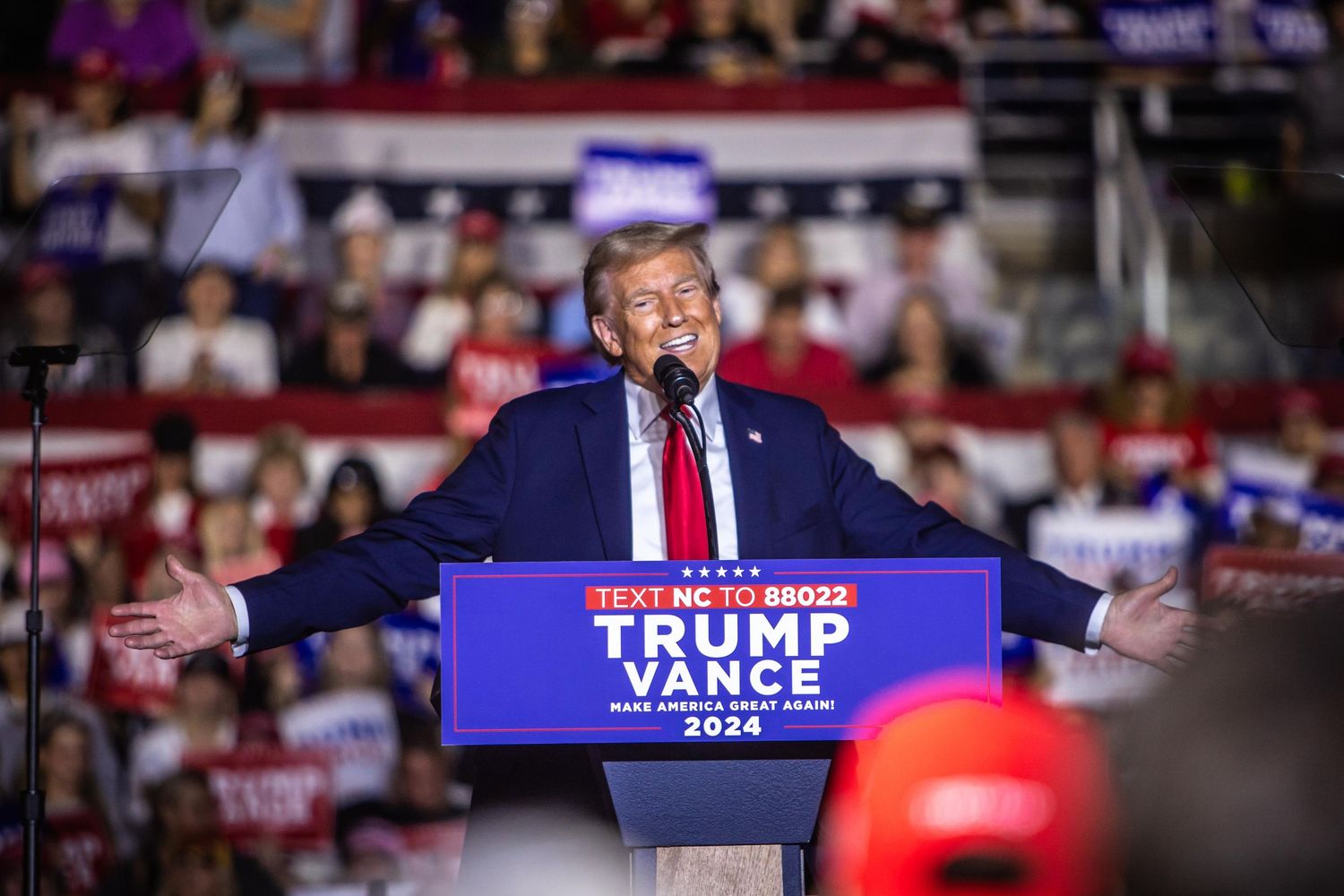 Donald Trump spreads his arms wide while speaking at a packed Trump Vance 2024 rally in North Carolina.