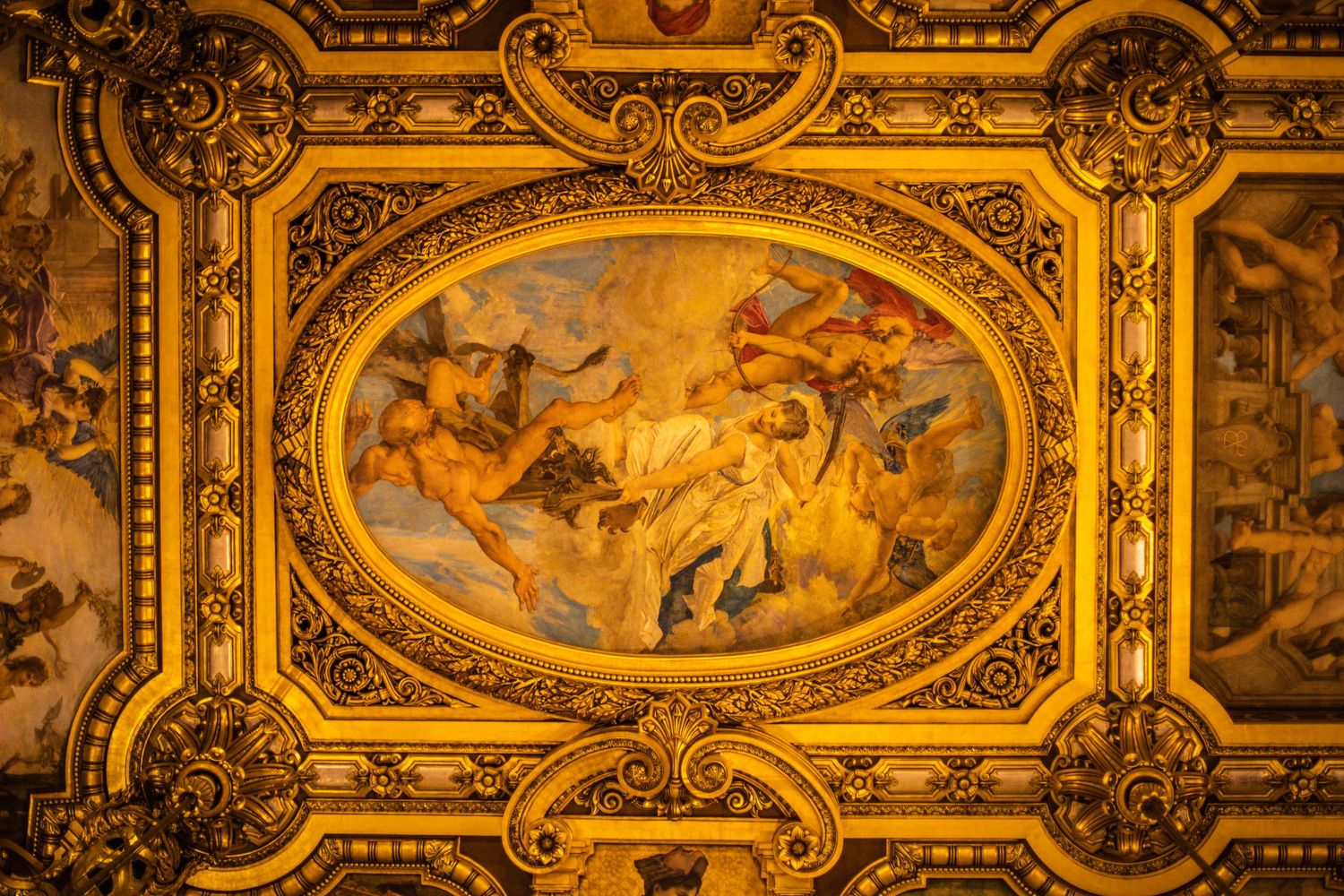 Ornate golden ceiling with an oval fresco painting depicting classical figures in a grand historic building.