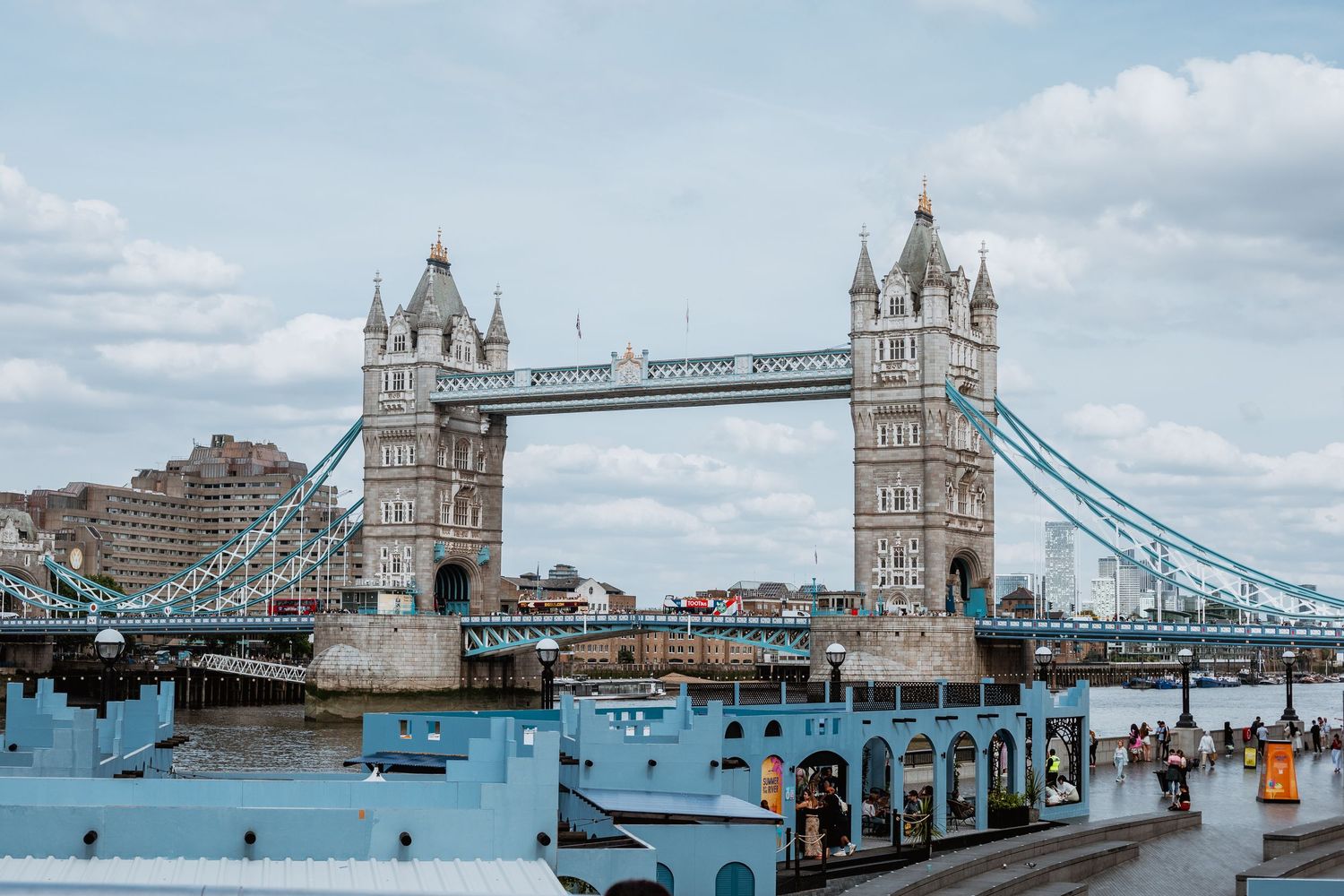 Iconic Tower Bridge spanning the River Thames in London, England, under a cloudy sky.