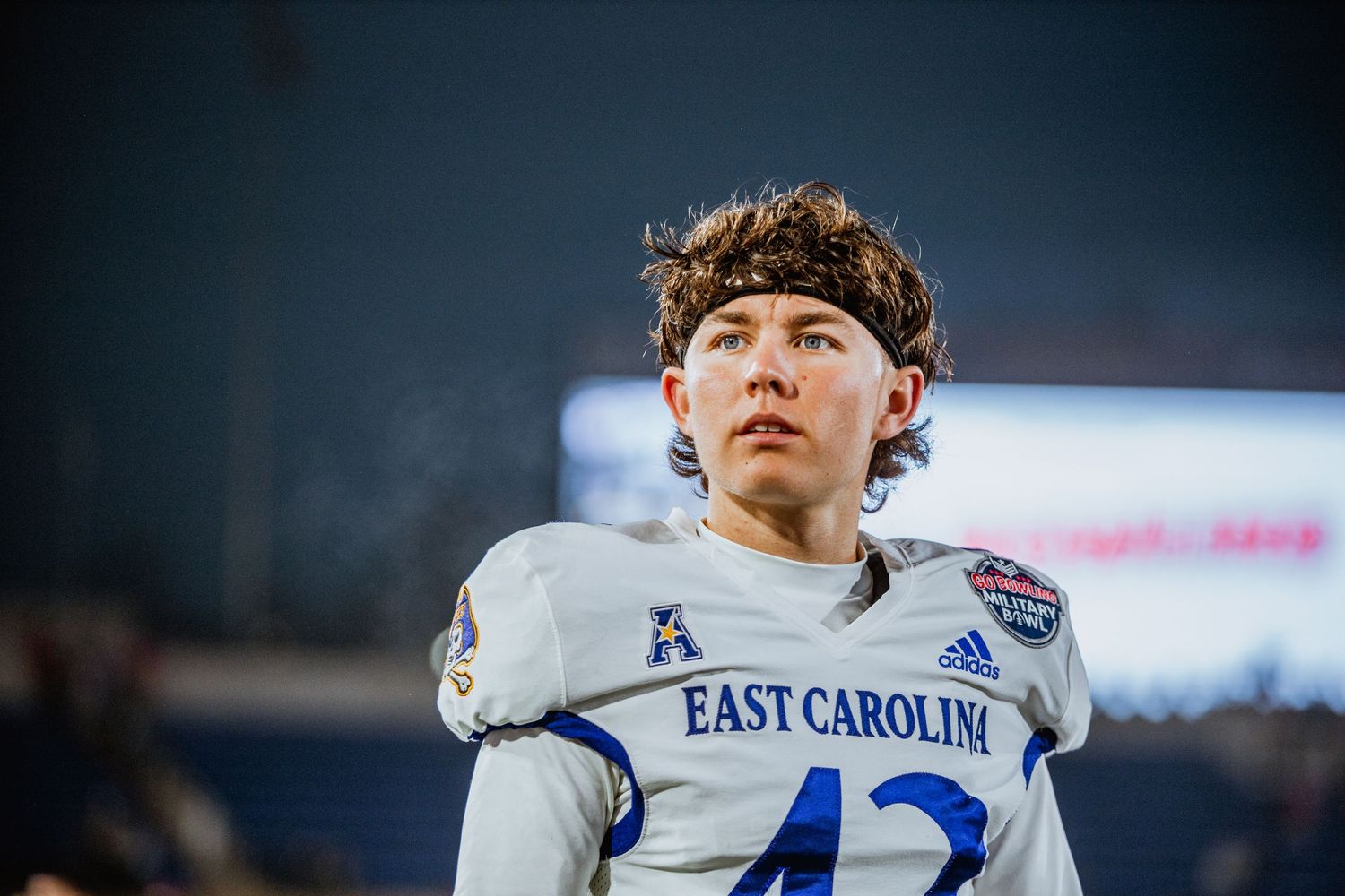 East Carolina Pirates football player number 42 in white uniform standing on sideline during bowl game.