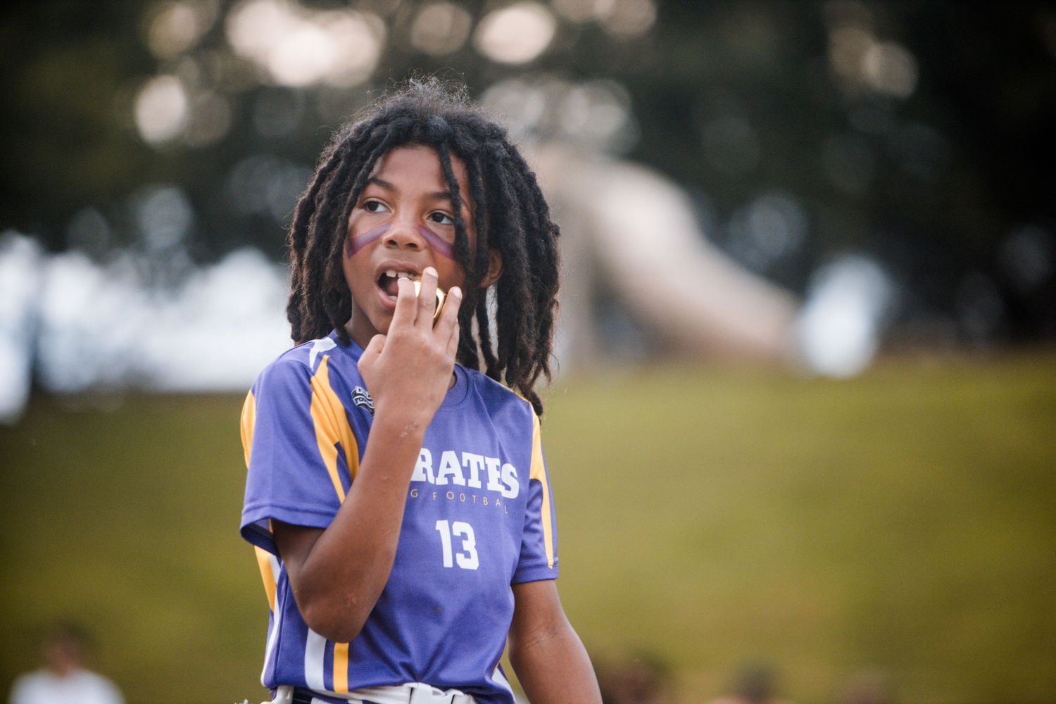 Young athlete in purple number 13 jersey reacts emotionally during a youth flag football game.