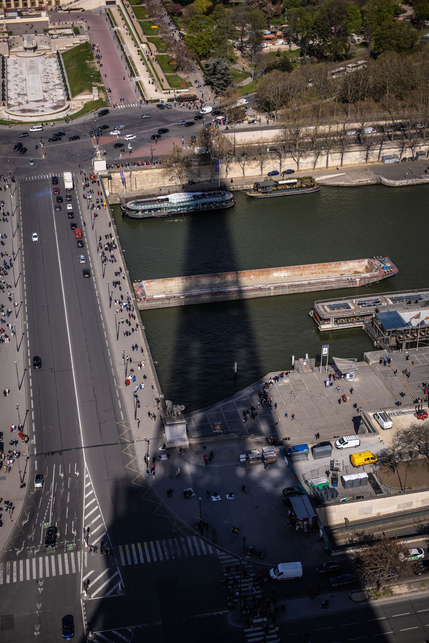 Aerial view of Paris showing the Eiffel Tower shadow stretching over the Seine River and busy streets below.
